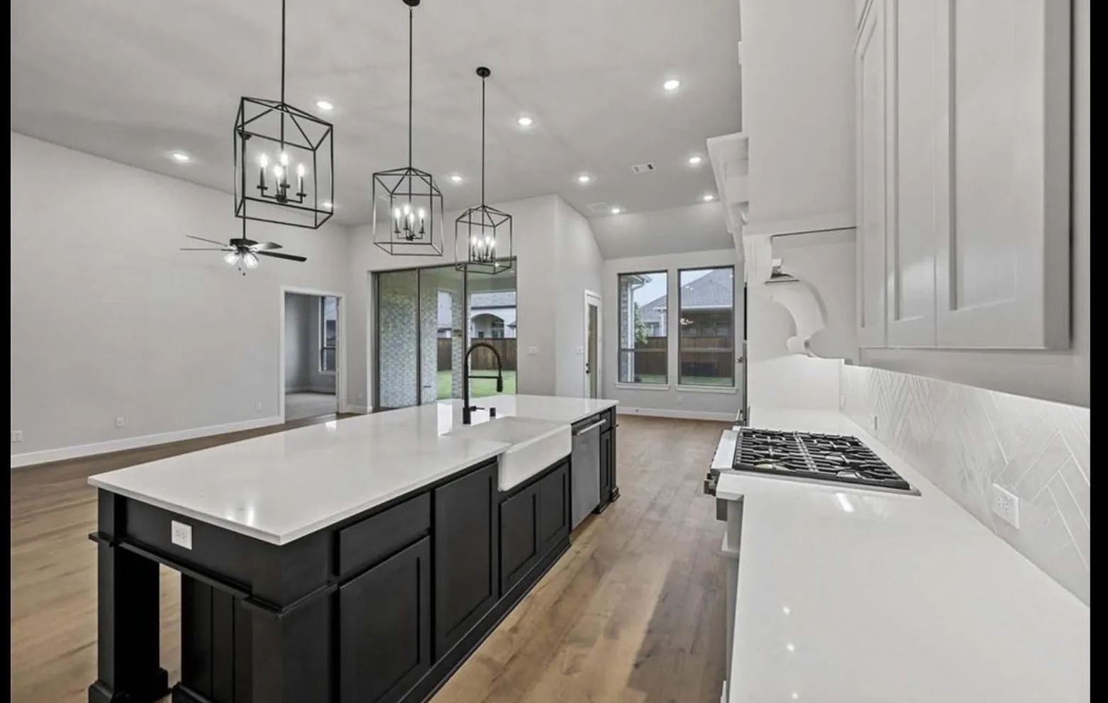 Expansive kitchen island with a farmhouse sink, integrated dishwasher, and pendant lighting