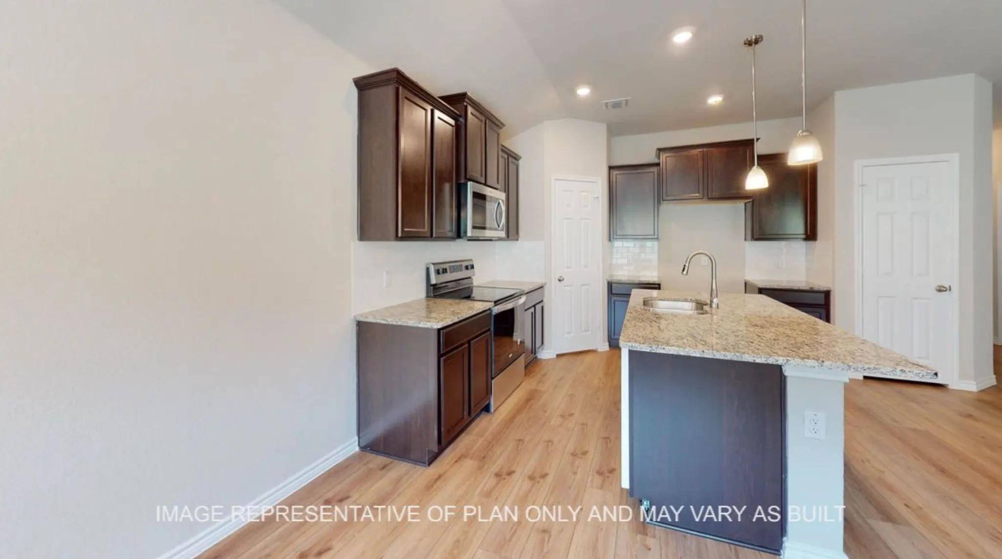 Kitchen featuring wood-finish flooring, dark wood cabinetry, granite countertops, stainless steel appliances, and a central island with an undermount sink