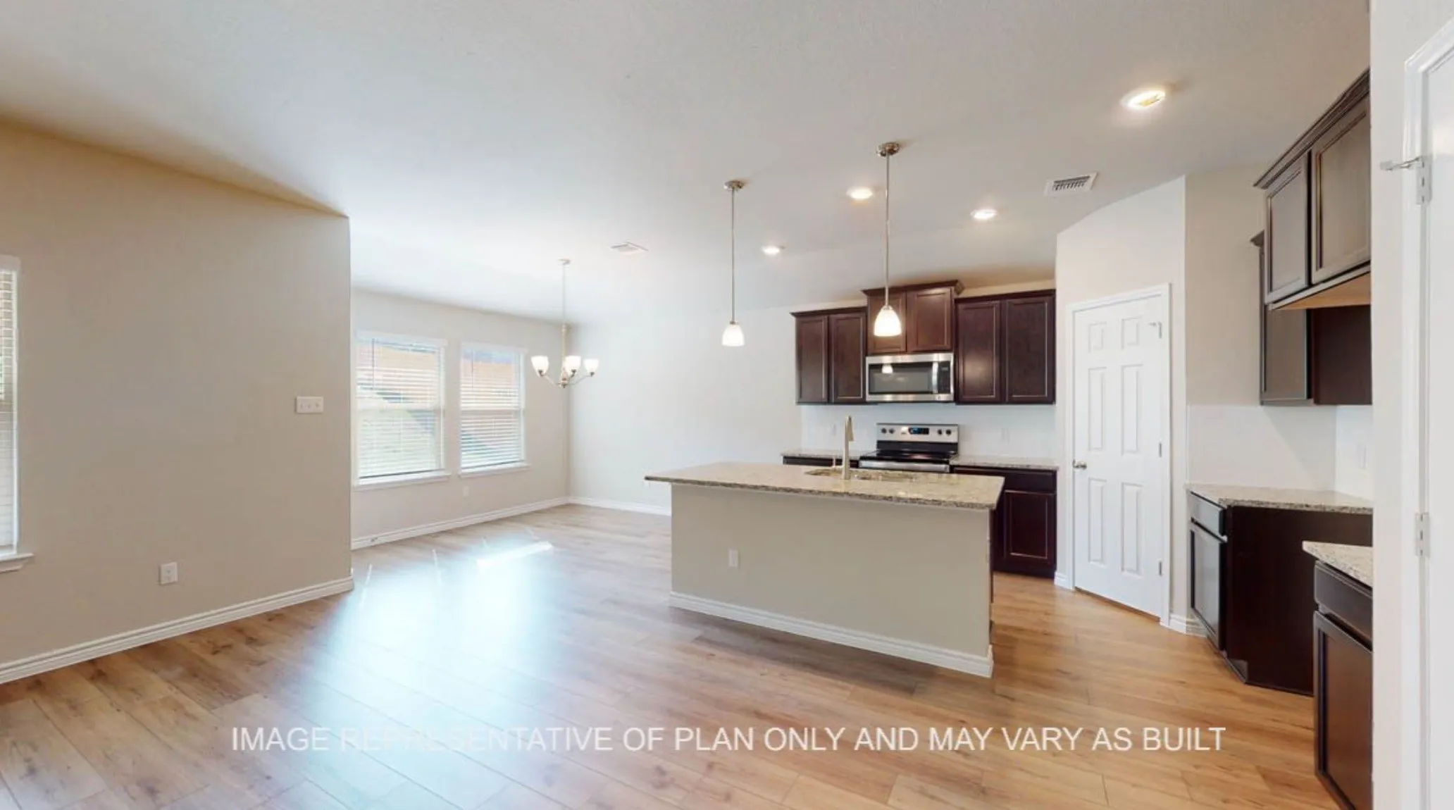Open-concept layout featuring wood-finish flooring, a kitchen island with pendant lighting, stainless steel appliances, and dark wood cabinetry