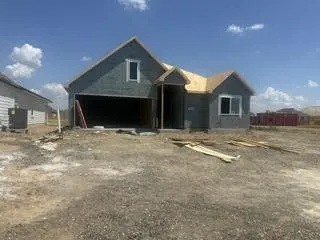 New construction residence featuring an attached garage and shingled roof under construction