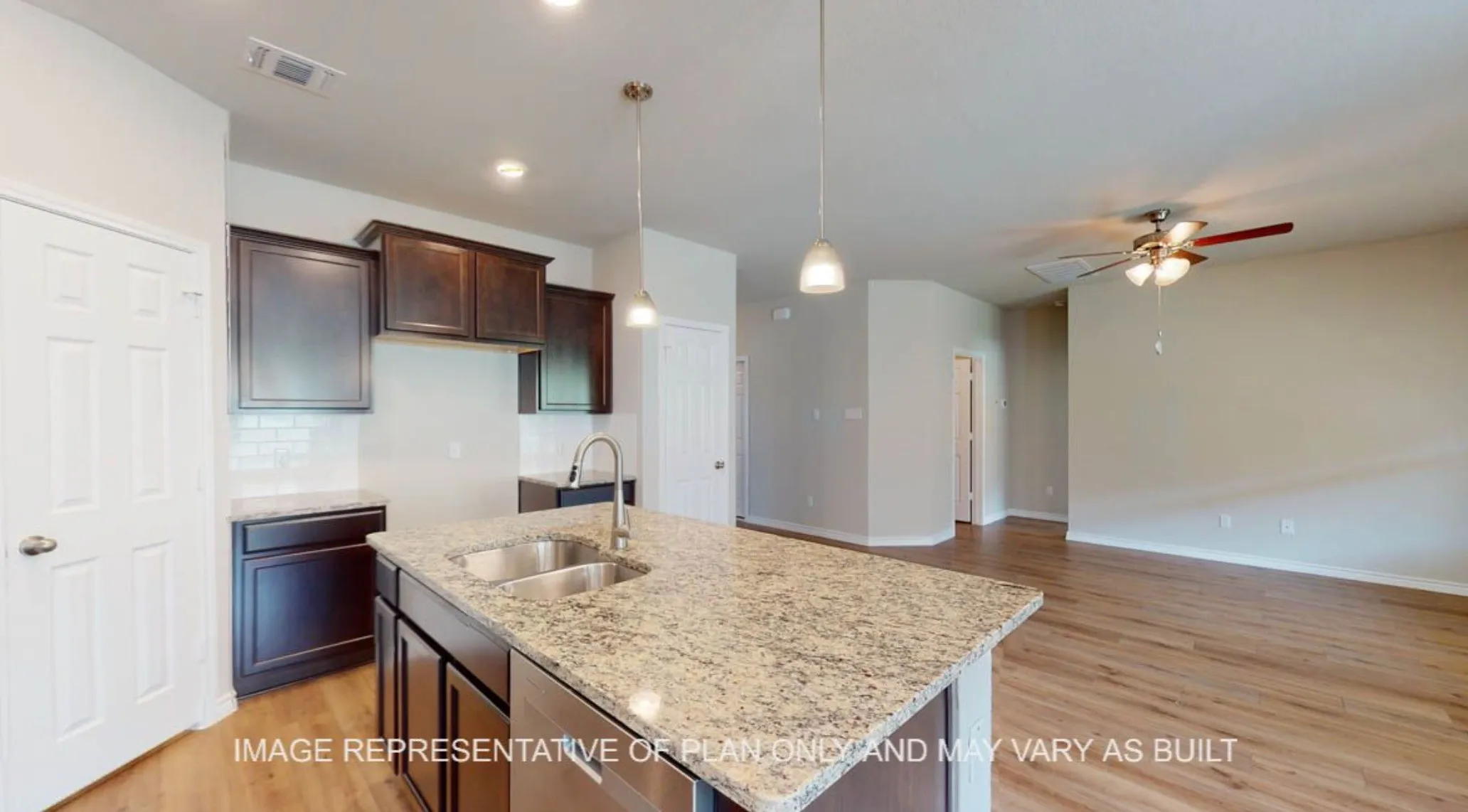 Kitchen island with dual basin sink and granite-style countertop, dark wood-finish cabinetry, subway tile backsplash, stainless steel appliances, and wood-finish flooring