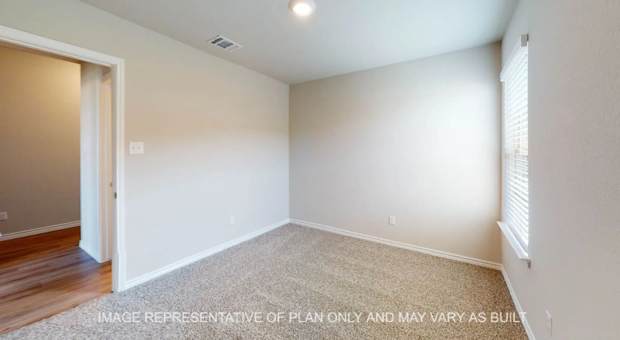 Neutral tone wall paint, textured carpet flooring, window with blinds, wood-finish flooring visible through doorway, ceiling-mounted light fixture