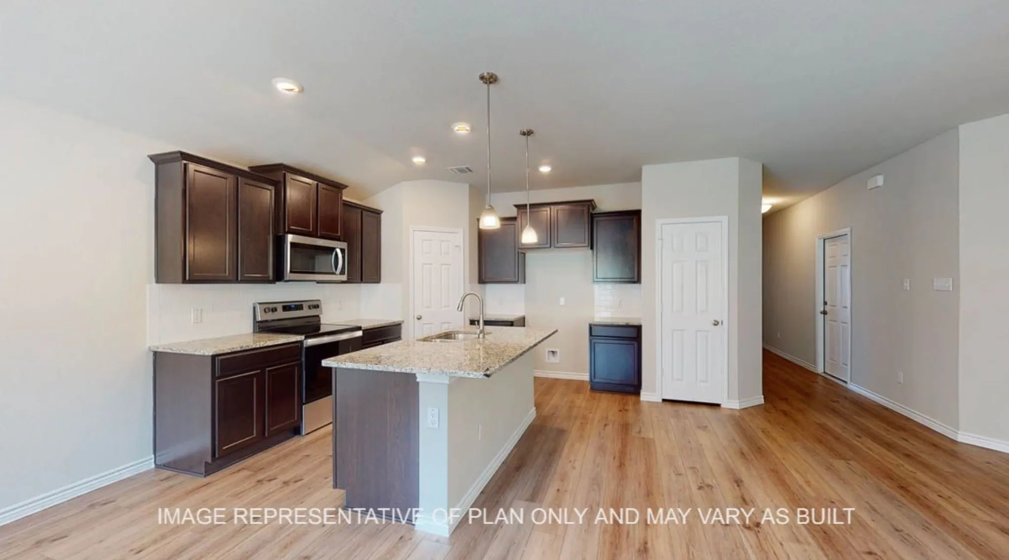 Kitchen featuring a central island with a sink, dark wood cabinetry, light-toned countertops, stainless steel appliances, and wood-finish flooring