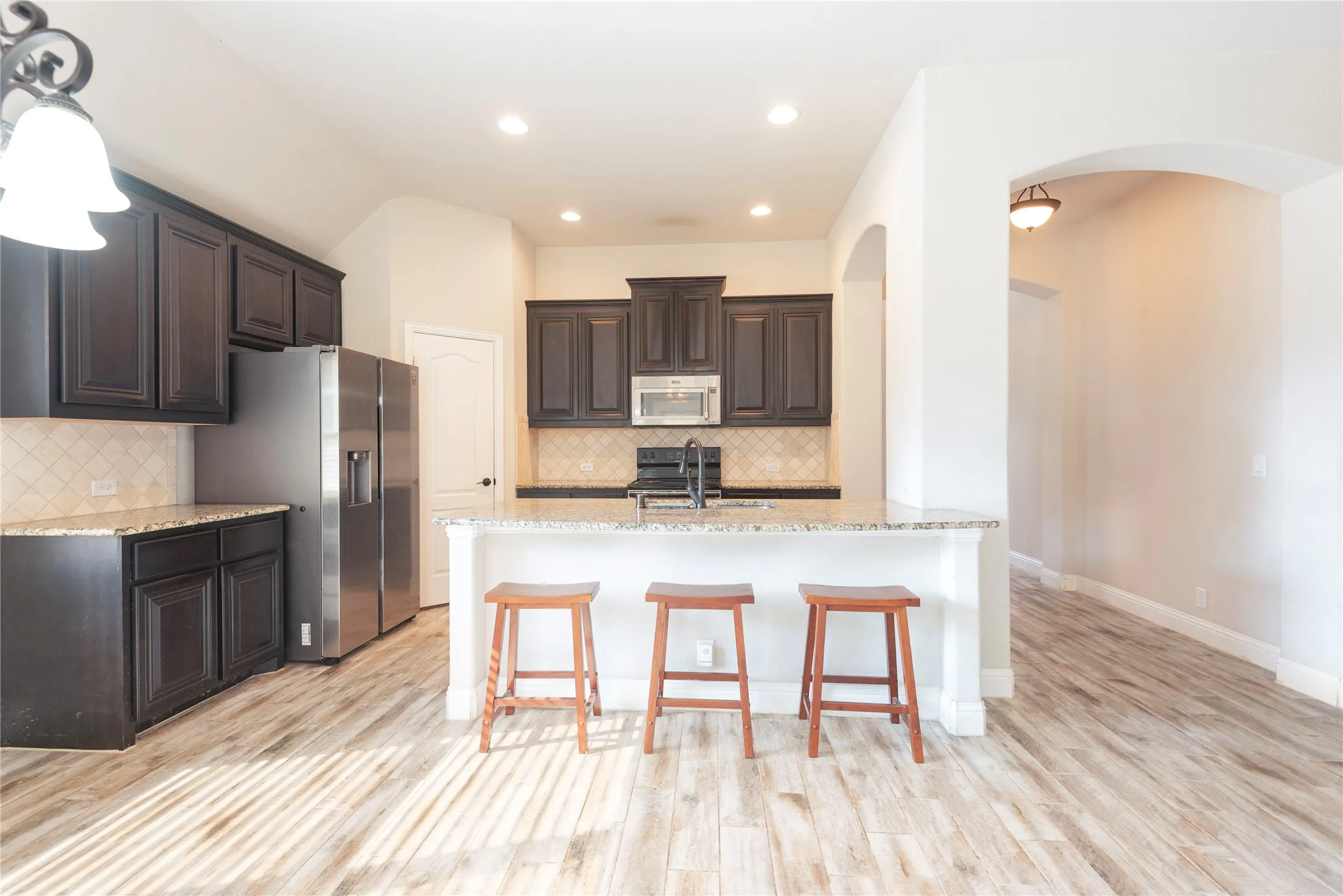 Kitchen featuring dark wood cabinetry, light-colored countertops, a tile backsplash