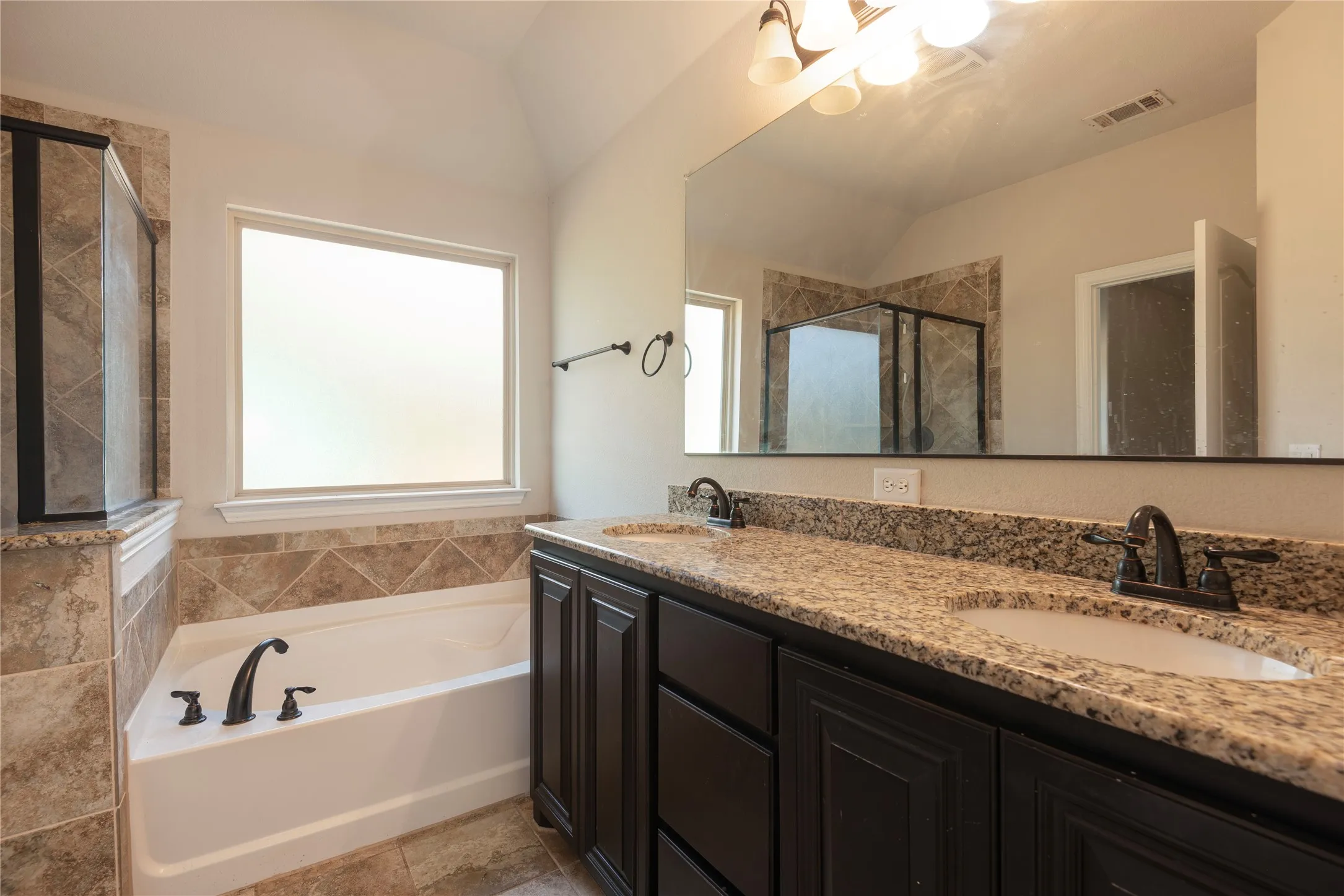 Upstairs bathroom Dual vanity with stone-finish countertop, dark wood-finish cabinetry, and oil-rubbed bronze fixtures
