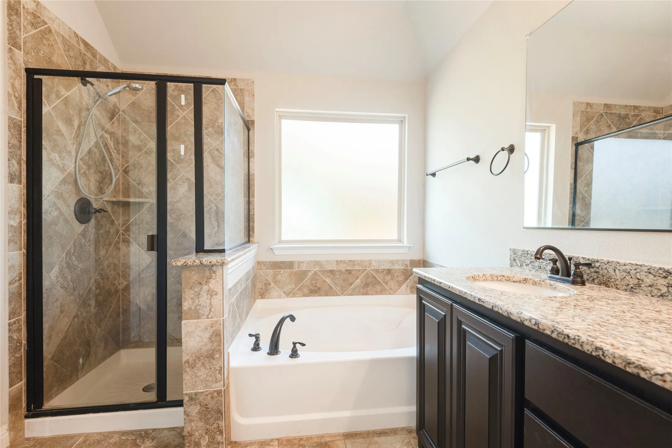 Upstairs bathroom Walk-in shower with tile surround, built-in soaking tub, single vanity with stone countertop, and wood-finish cabinetry