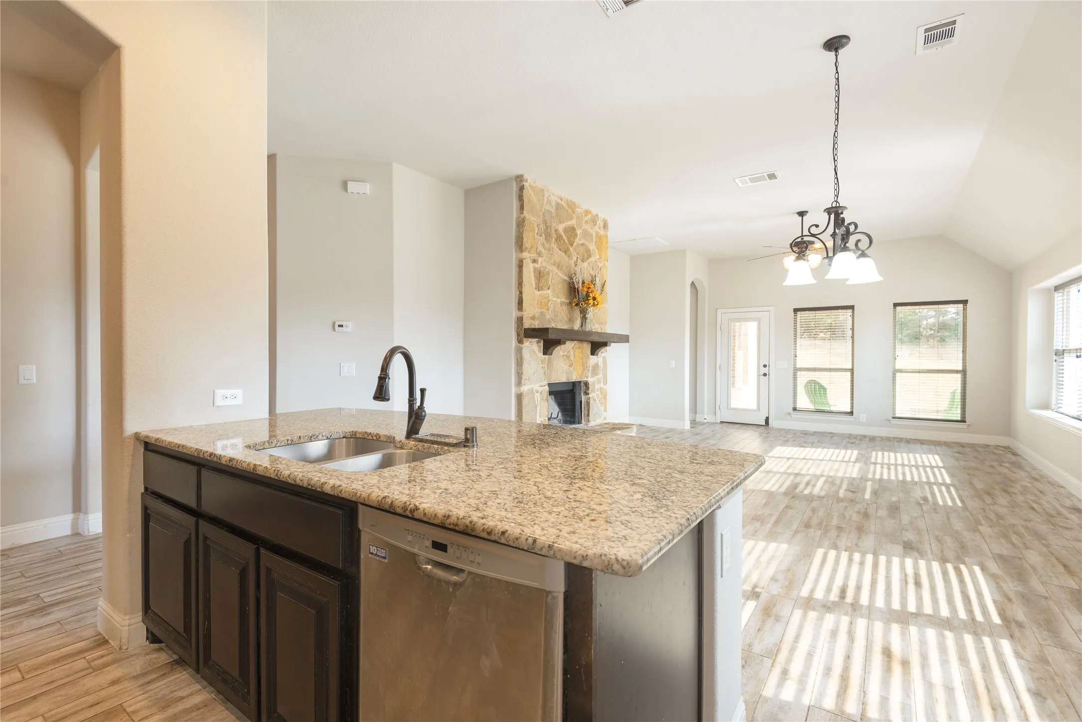 Kitchen island with granite countertop, stainless steel sink, and dark wood-finish cabinetry