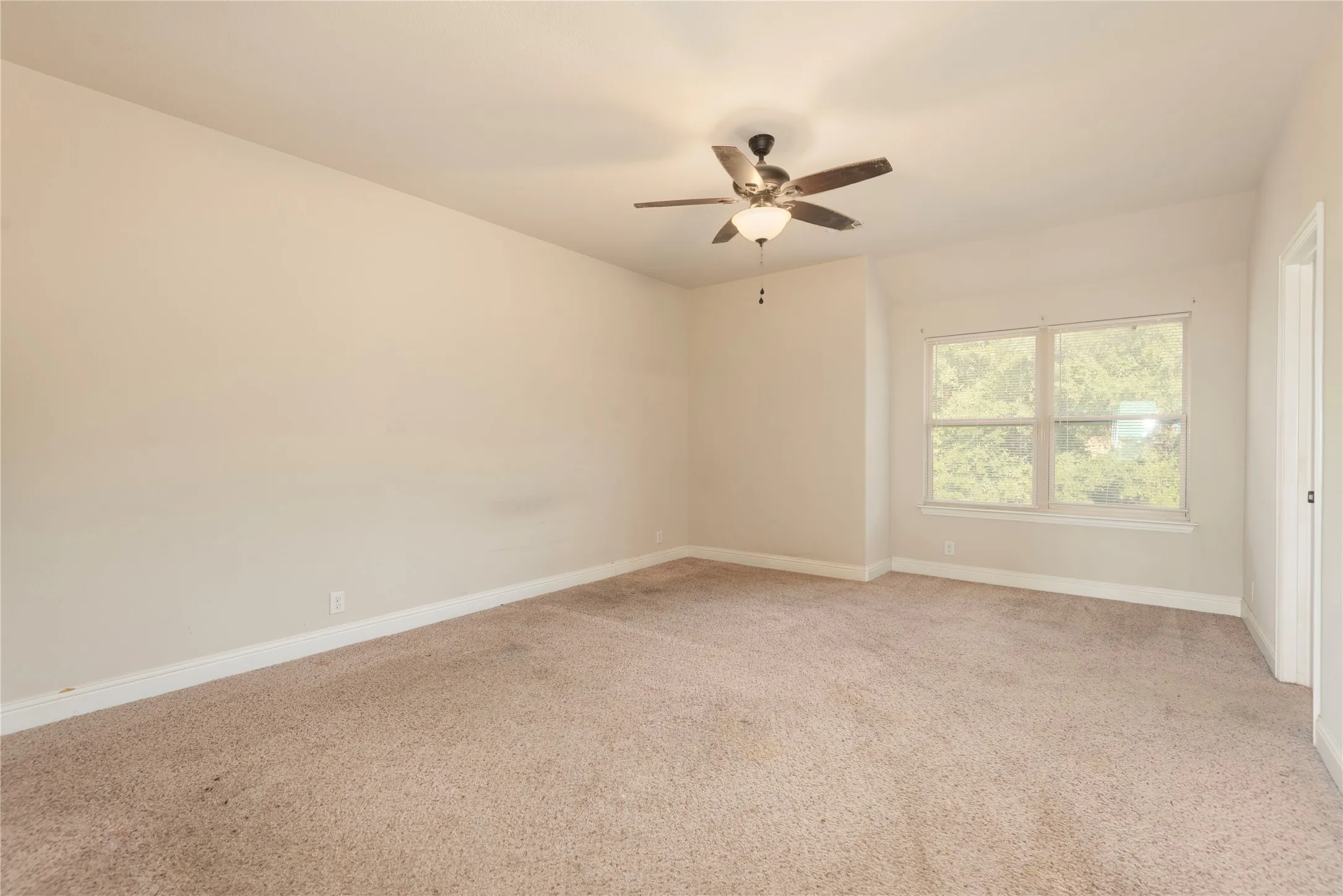 Spacious 2nd primary bedroom upstairs. featuring neutral carpeting, a dual-pane window, and a ceiling fan with integrated lighting