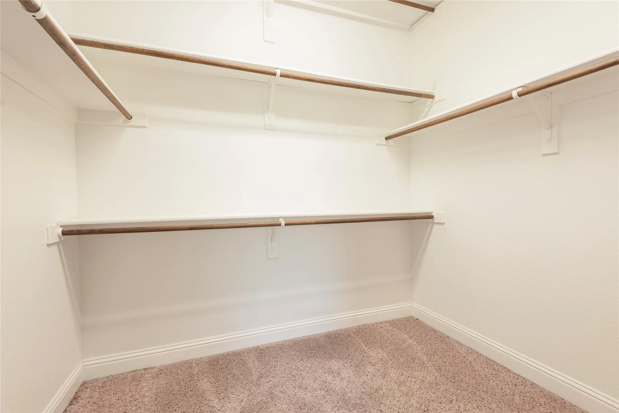 Carpeted closet with multiple shelving and hanging rods