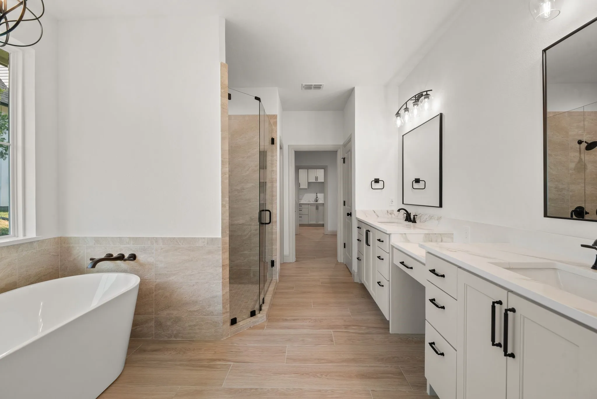 Spa-inspired primary bathroom combines a freestanding soaking tub, double vanity, custom cabinetry, and elegant modern finishes.