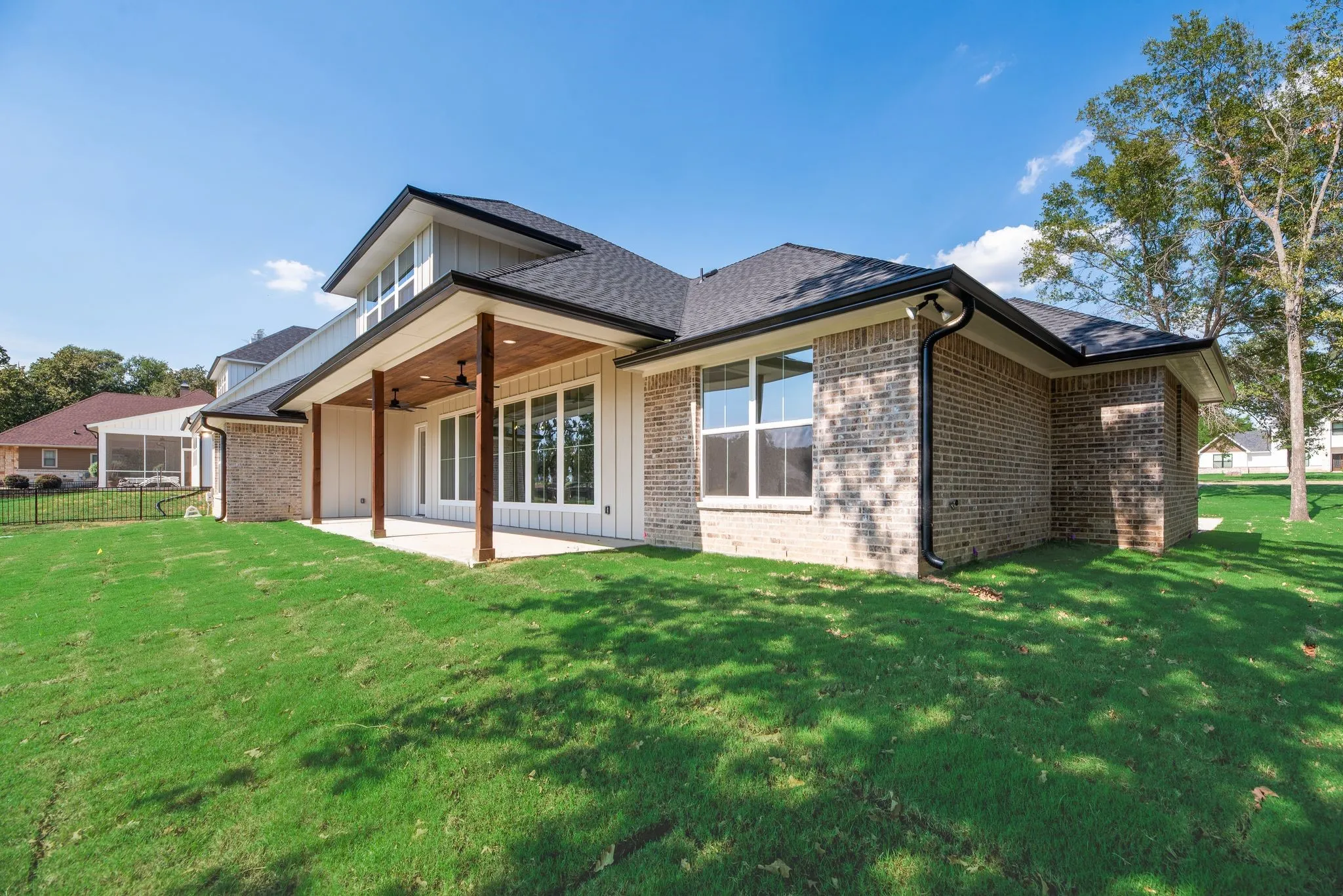 Rear exterior showcases the home's modern farmhouse architecture, large windows, covered porch, and freshly sodded backyard.