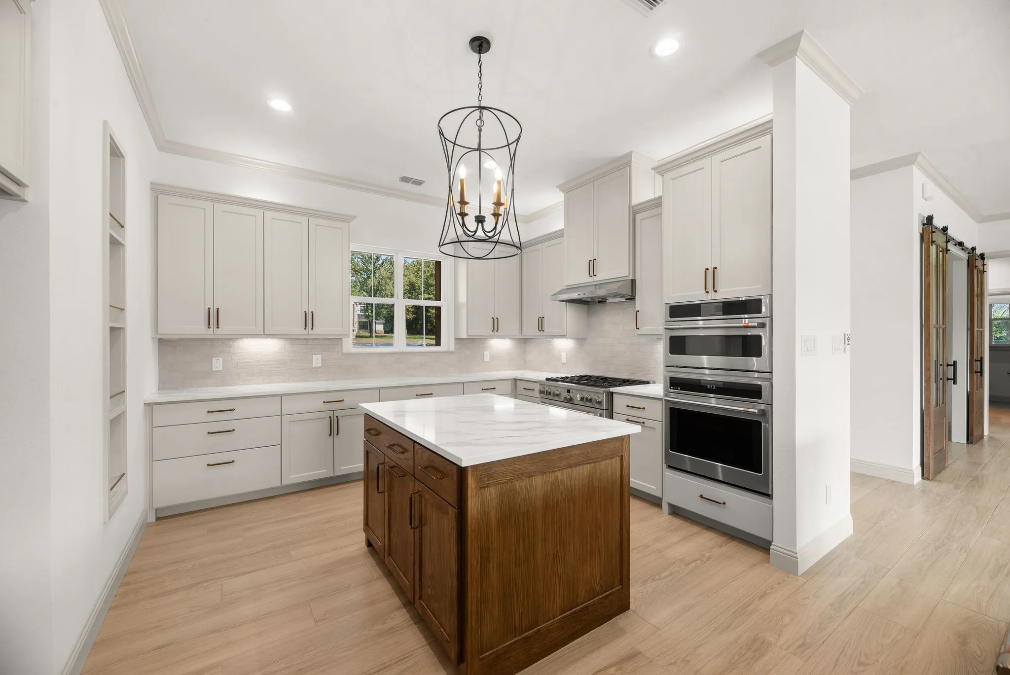 Custom kitchen features beautiful cabinetry, quartzite countertops, designer lighting, and a dedicated wood-toned prep island.