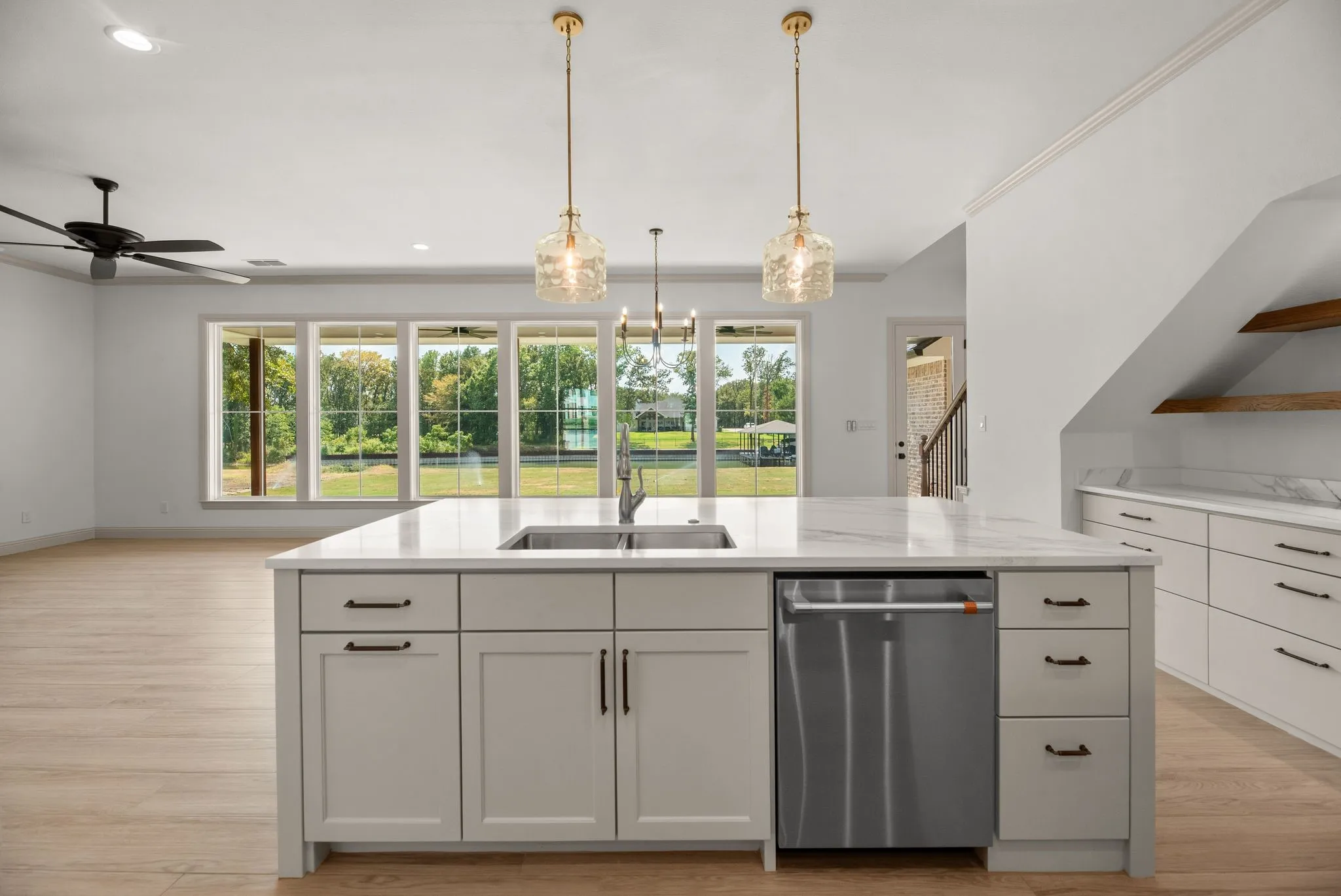 Bright kitchen showcases expansive windows, quartzite surfaces, designer lighting, and thoughtfully planned work and gathering areas.