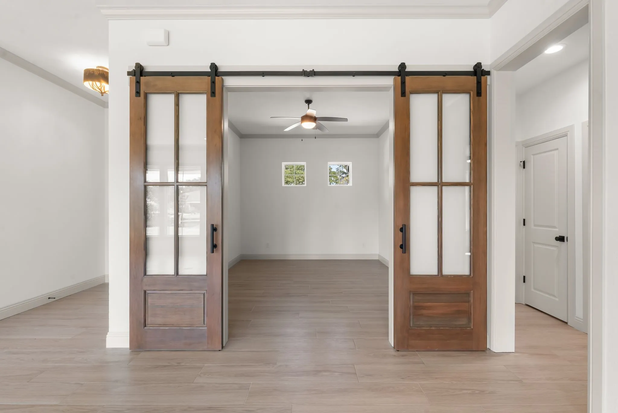Stylish sliding barn doors open to a dedicated home office, adding functionality and modern farmhouse character to the floor plan.
