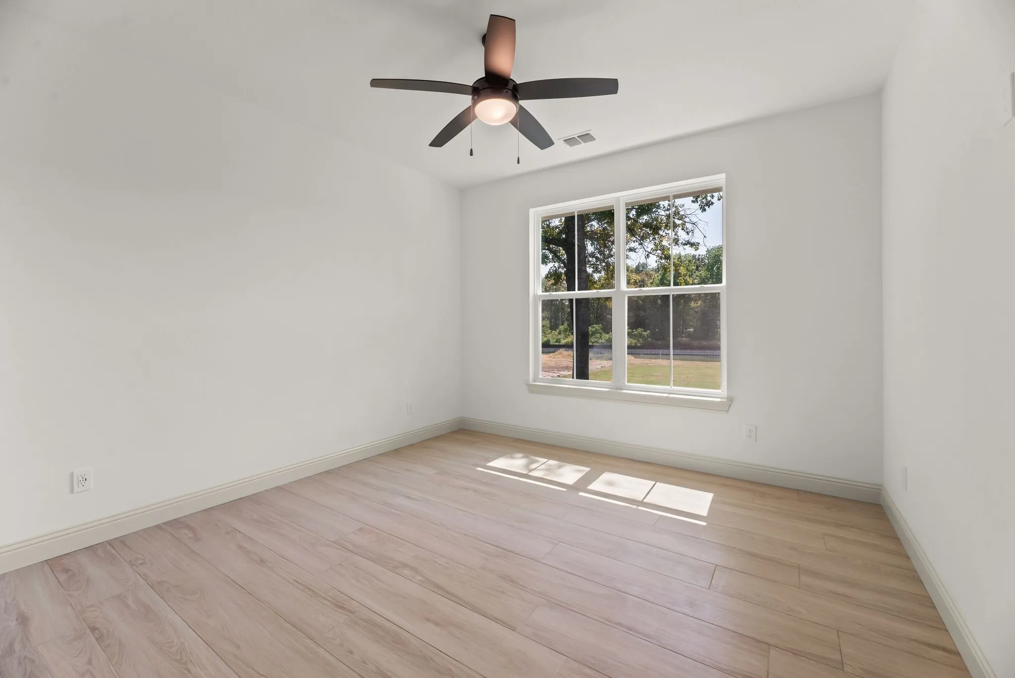Bright secondary bedroom offers attractive hard-surface flooring, natural light, and comfortable space for family or lake house guests.