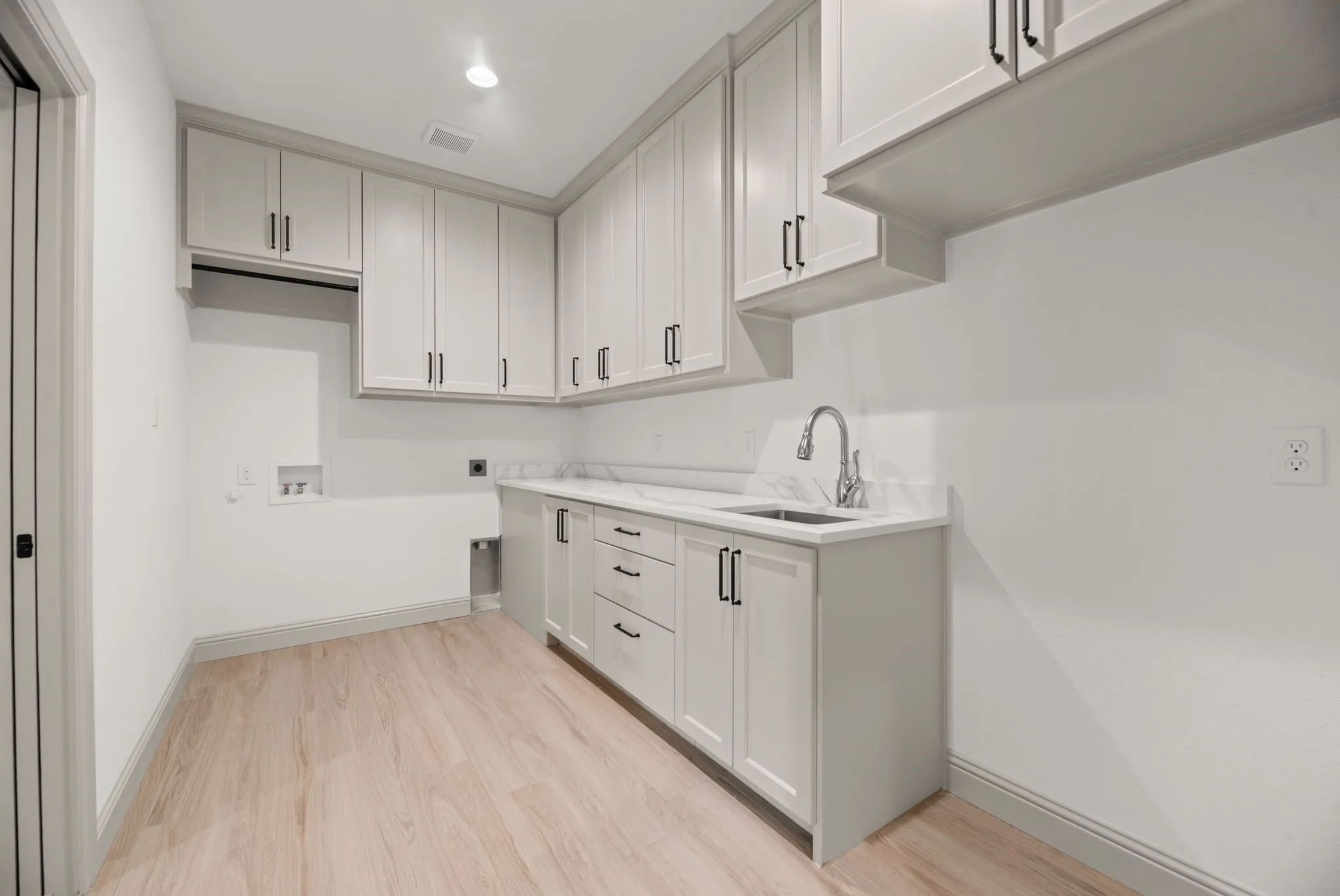Dedicated laundry room features built-in cabinetry, utility sink, workspace, and convenient storage for everyday organization.