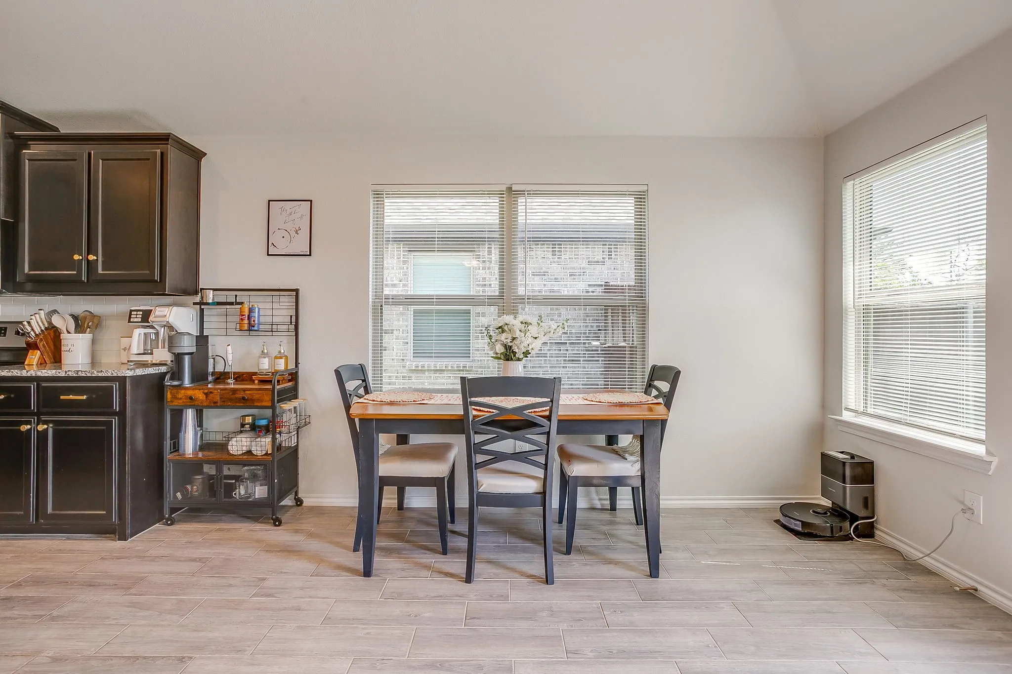 Kitchen area featuring dark cabinetry, speckled countertops, a subway tile backsplash, and light wood-finish flooring