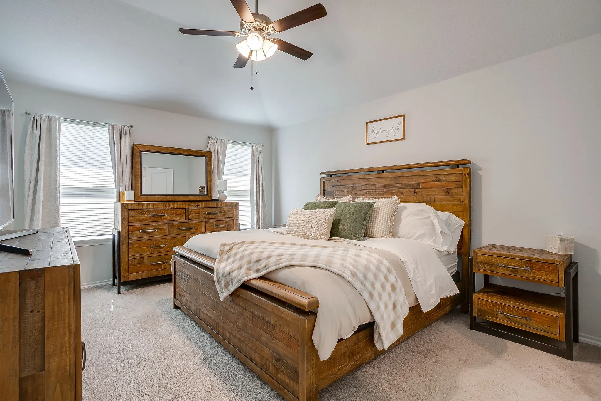 Vaulted ceiling with an attached ceiling fan, two windows with blinds, and light-toned carpeting