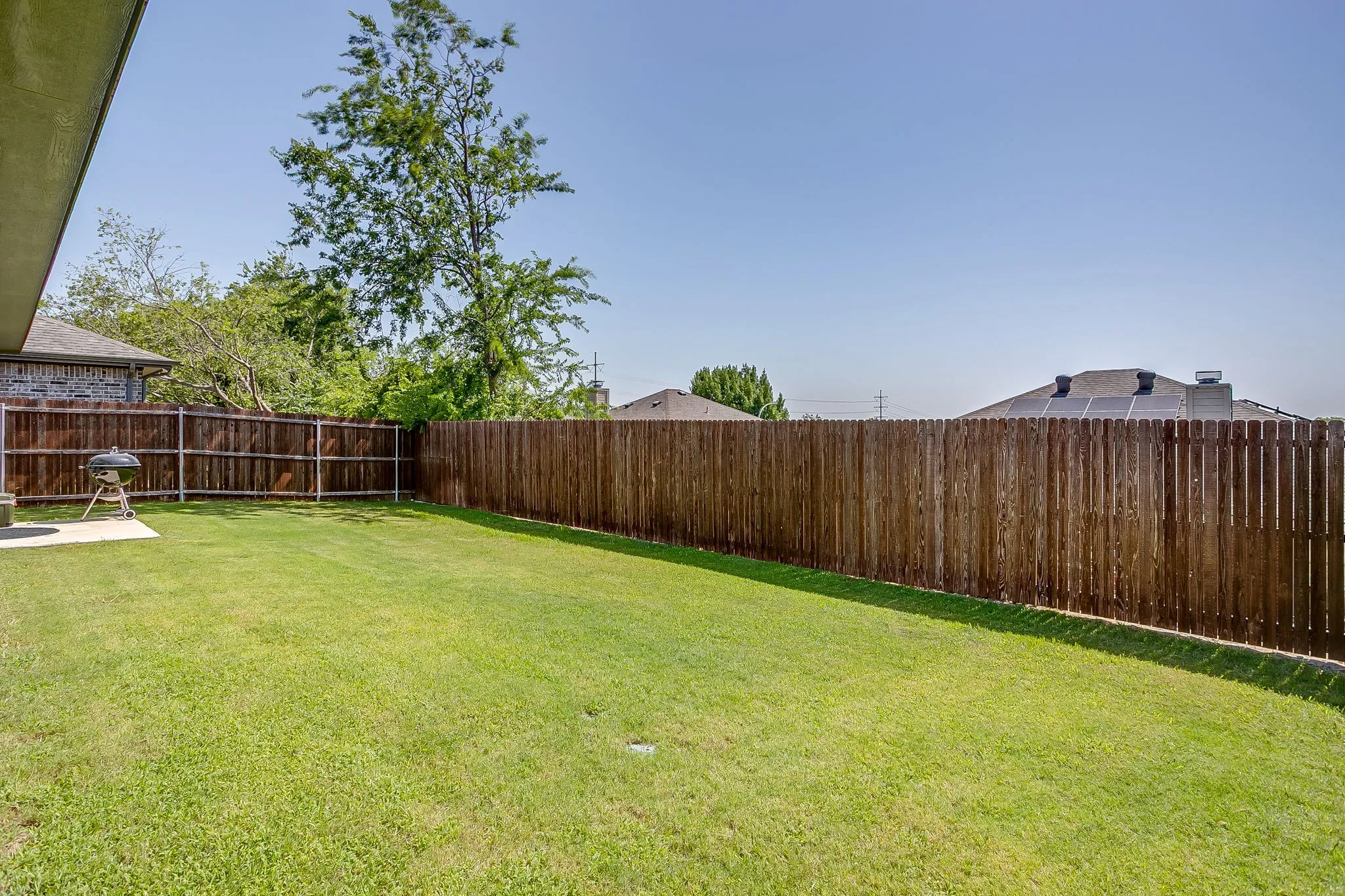 Expansive backyard featuring a manicured lawn, a full privacy fence, and a concrete patio pad