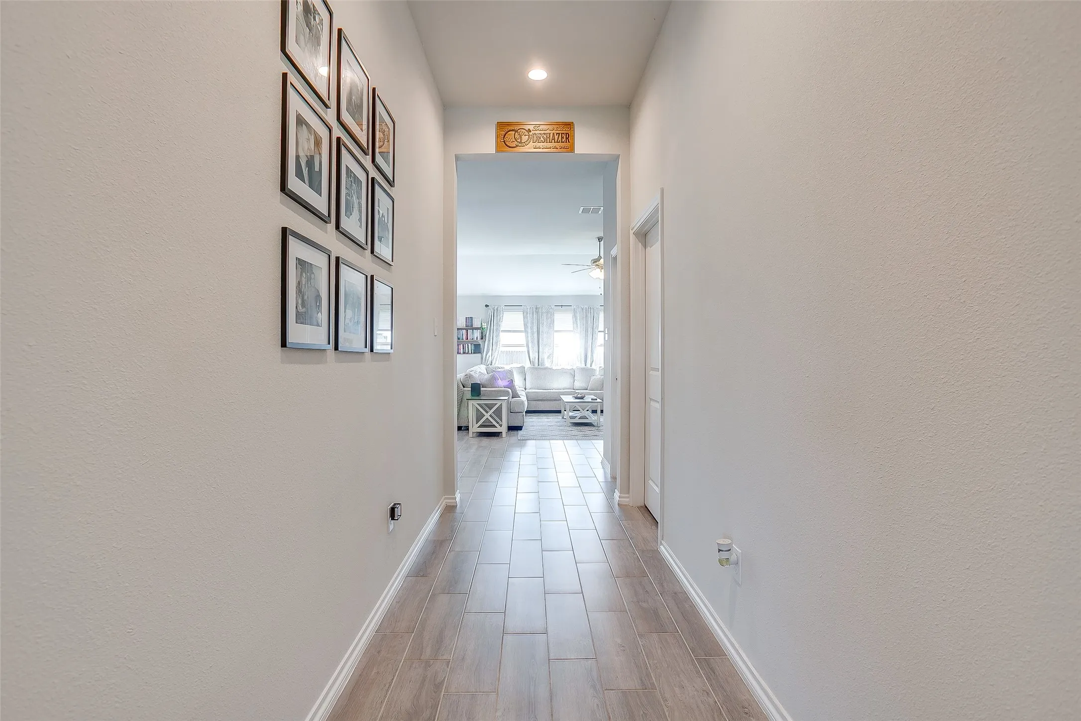 Hallway featuring light-toned walls, wood-finish tile flooring, recessed lighting, and white trim