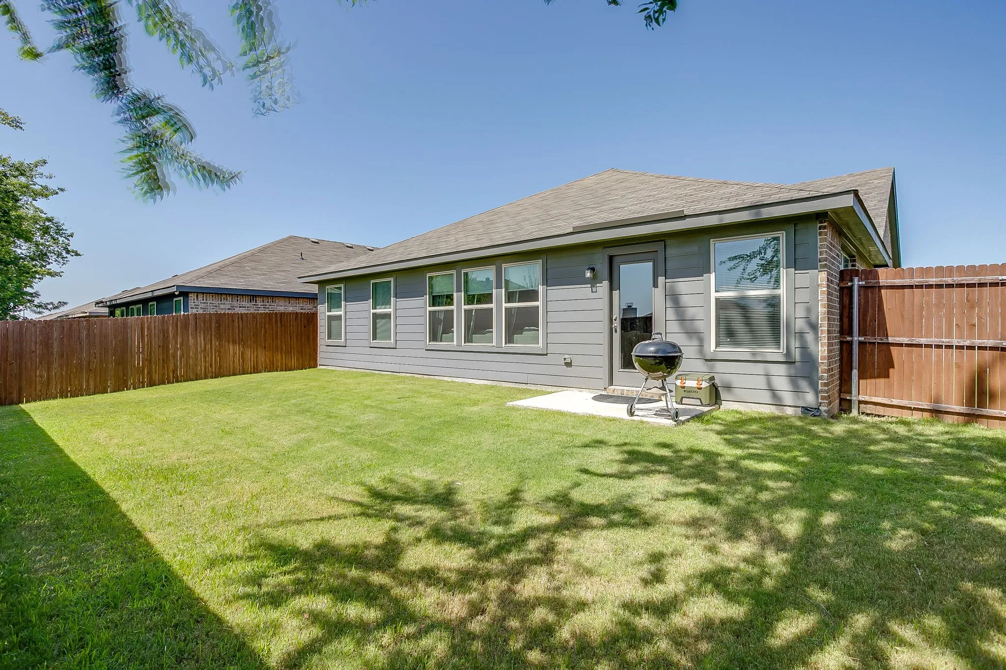 Expansive green lawn, a privacy fence, and a concrete patio