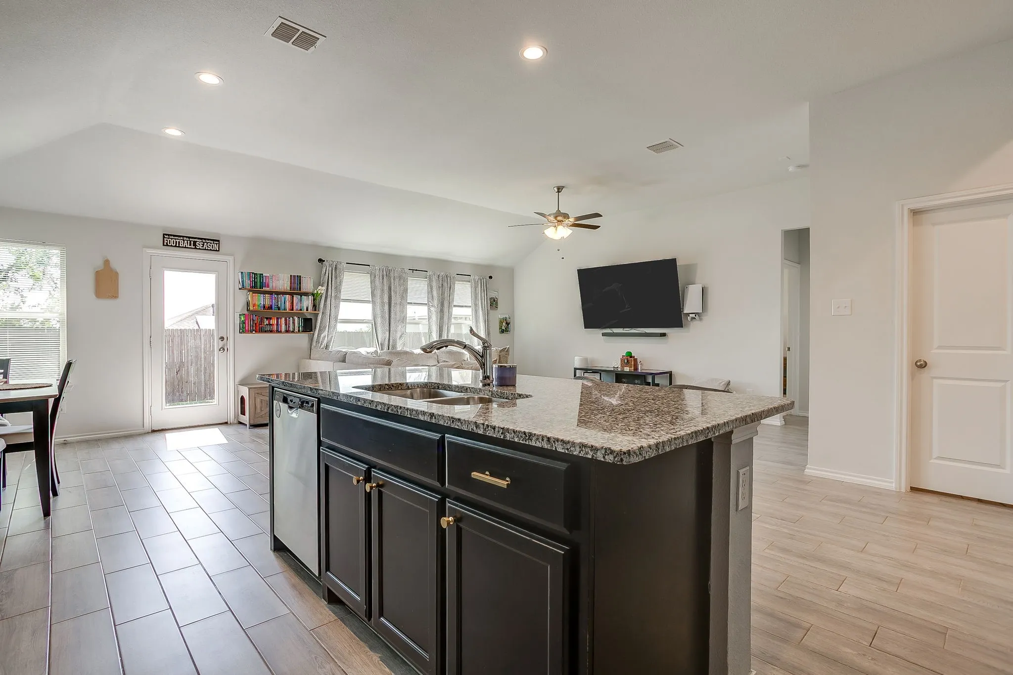 Kitchen island with a granite-style countertop, stainless steel sink, and dark wood cabinetry