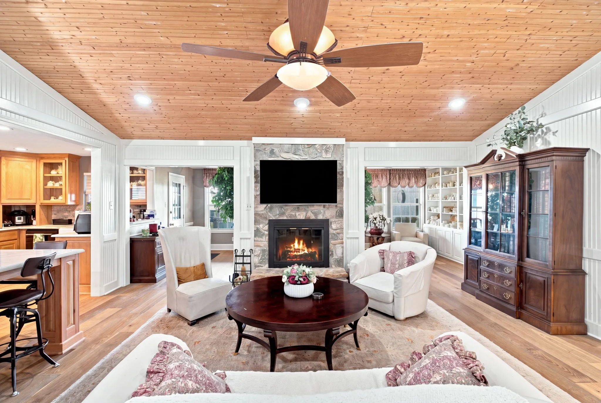 Wood-finish flooring and a wood-paneled ceiling with a central ceiling fan