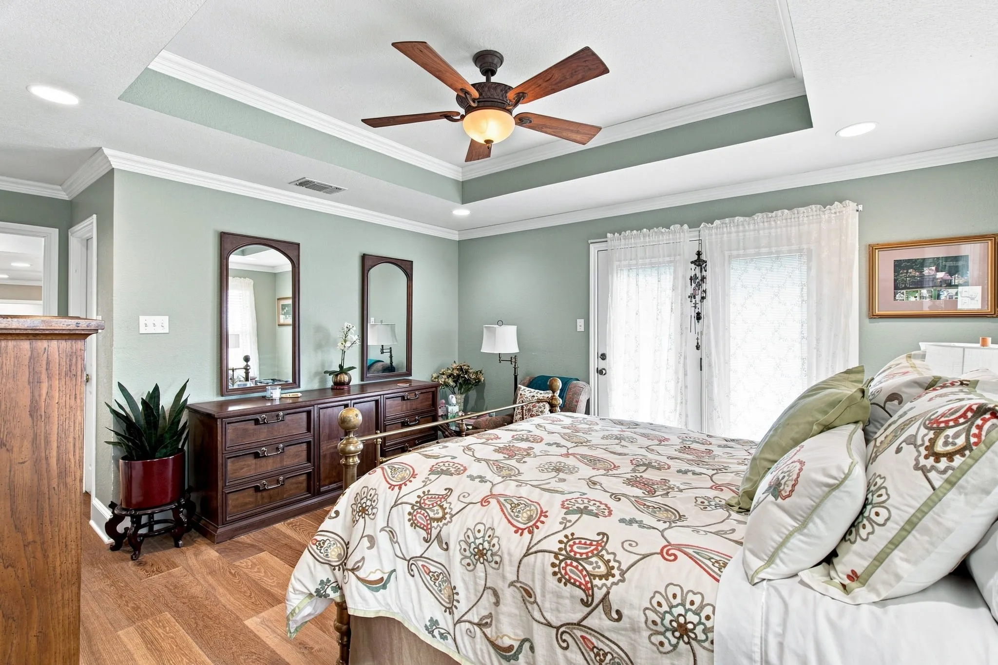 Tray ceiling with recessed lighting and a ceiling fan, wood-finish flooring, and double French doors with transom windows