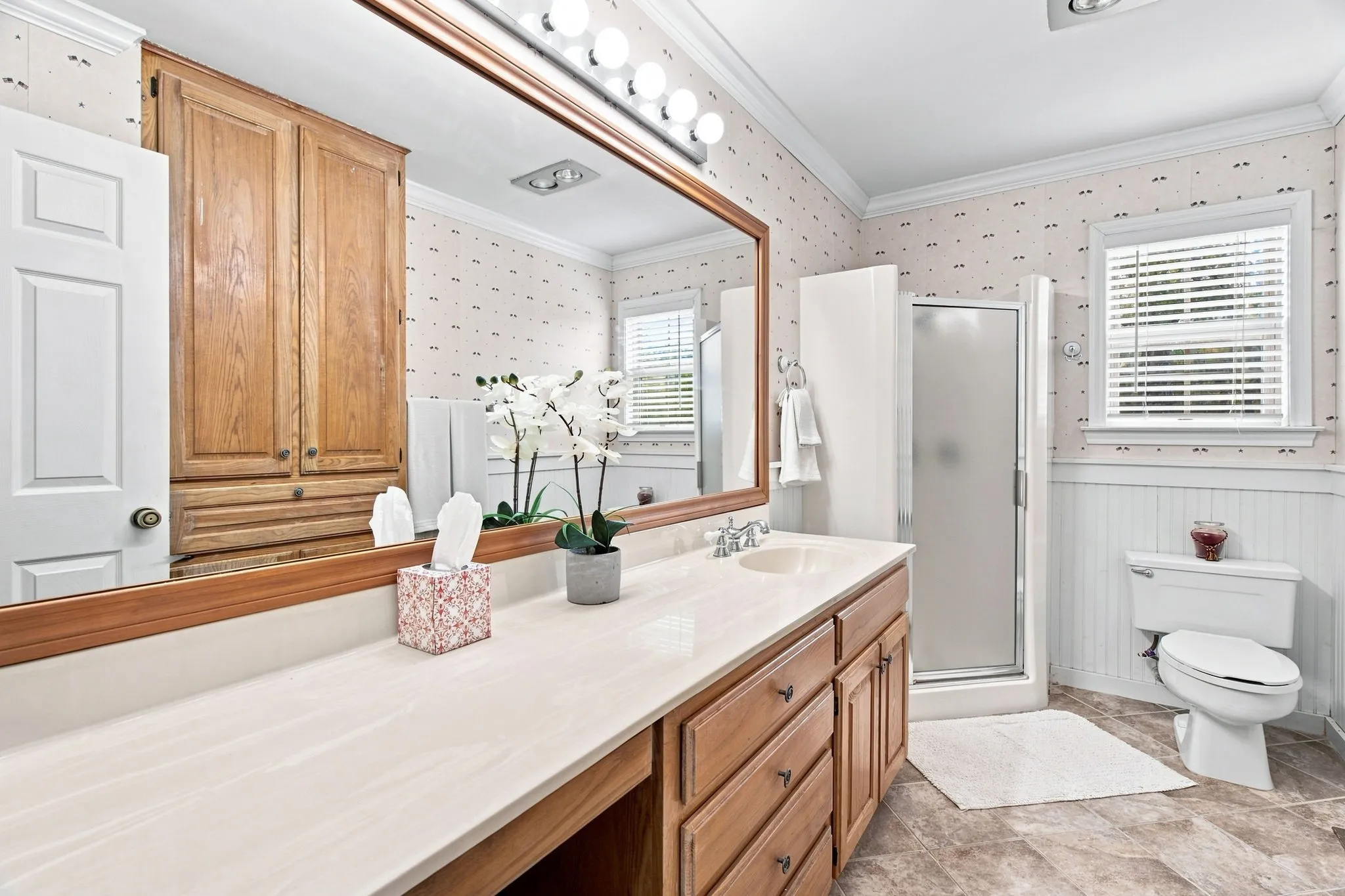 Double vanity with an integrated sink, framed mirror, built-in wooden cabinetry, and shower with frosted glass enclosure
