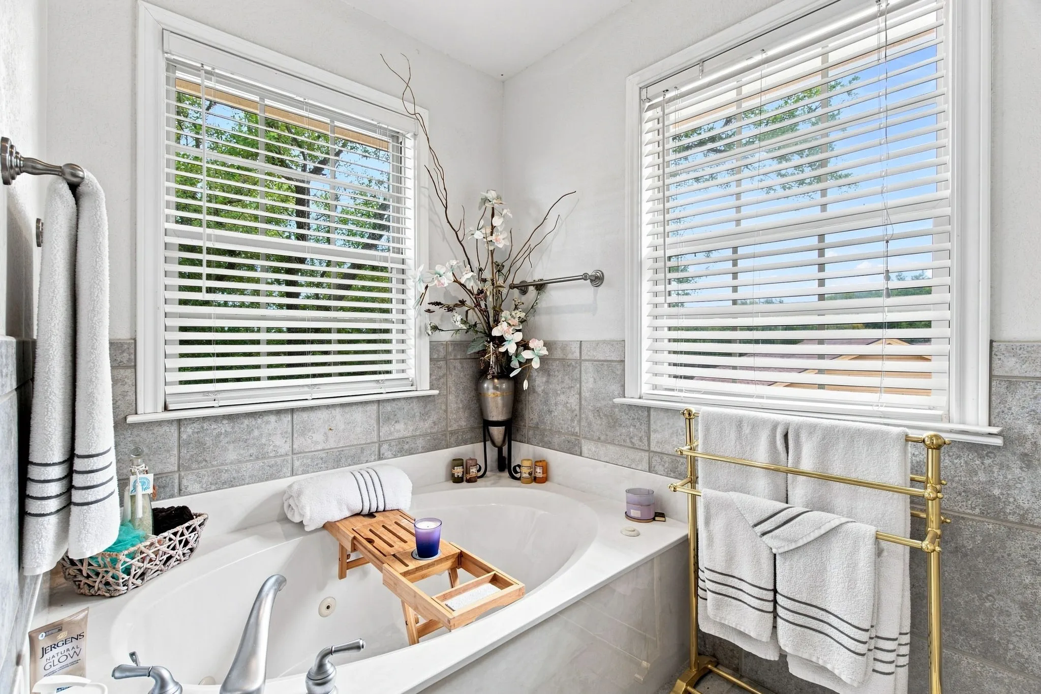Built-in soaking tub with deck-mounted faucet, surrounded by large format wall tile