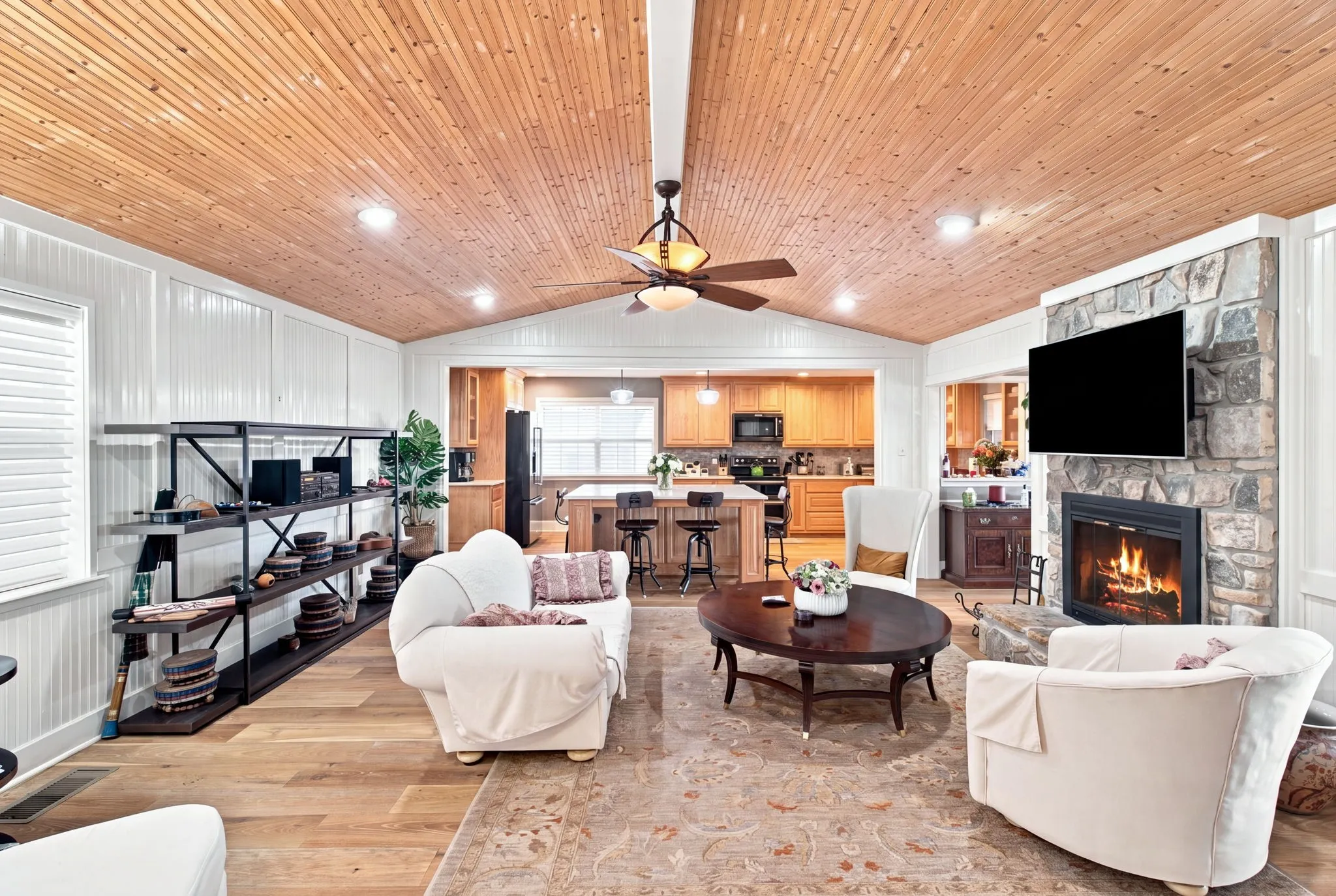 Vaulted wood-paneled ceiling with recessed lighting, stone fireplace, wood-finish flooring, and a ceiling fan