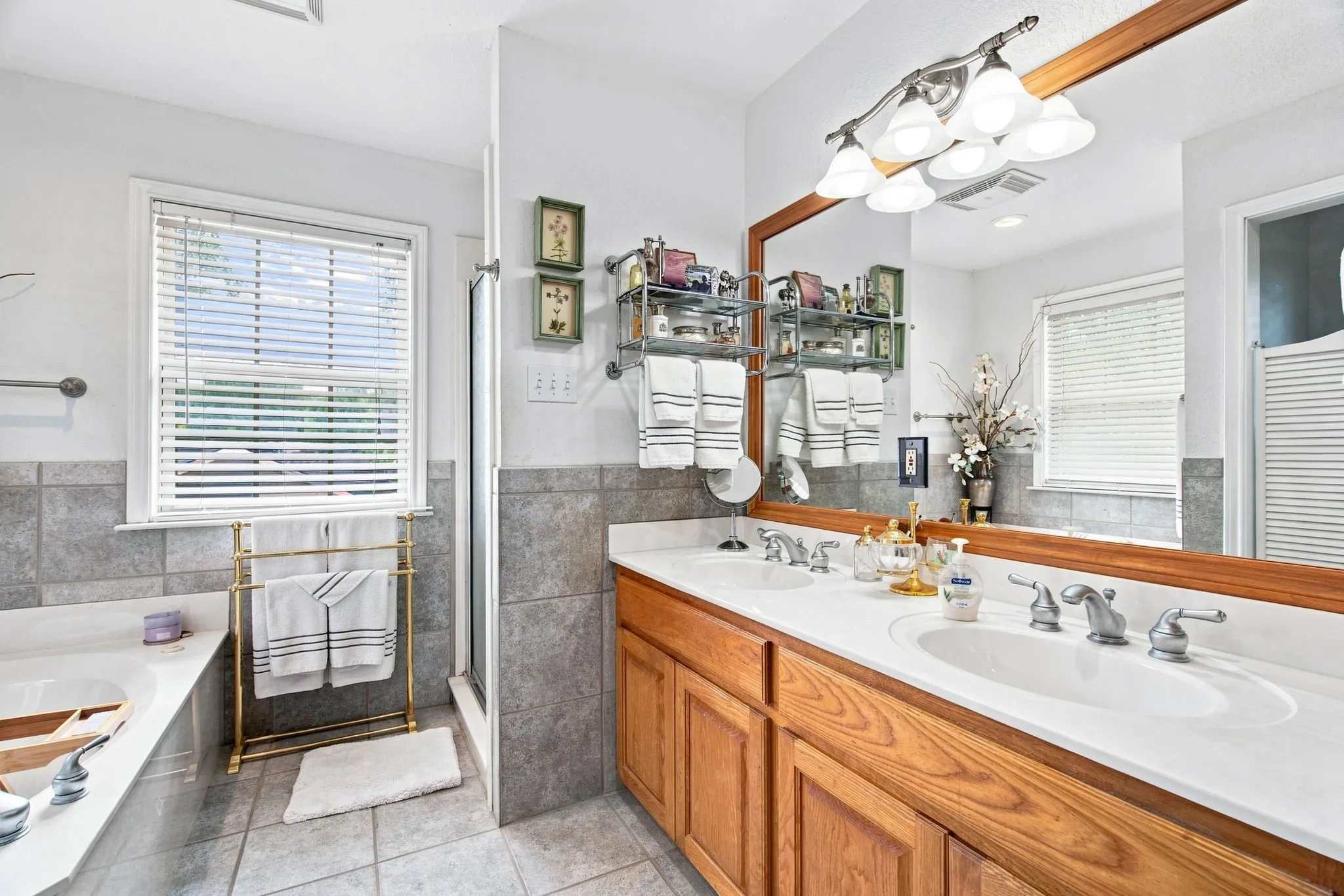 Dual vanity with wood cabinetry, large mirror, and overhead lighting