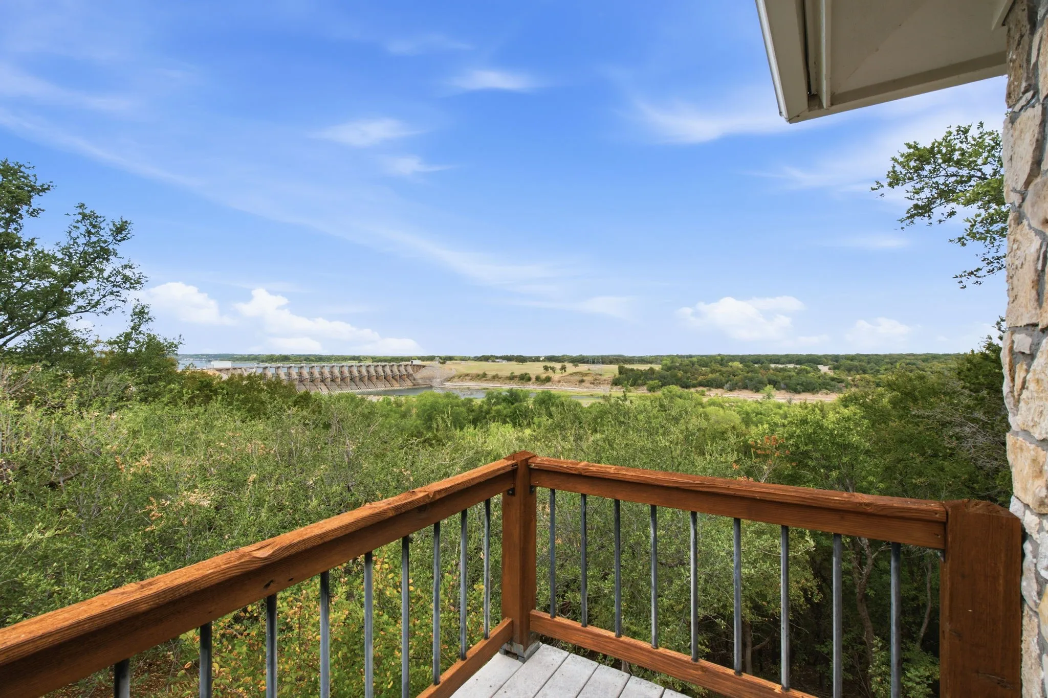 Expansive outdoor balcony with wood railing, metal balusters, and wood-finish decking