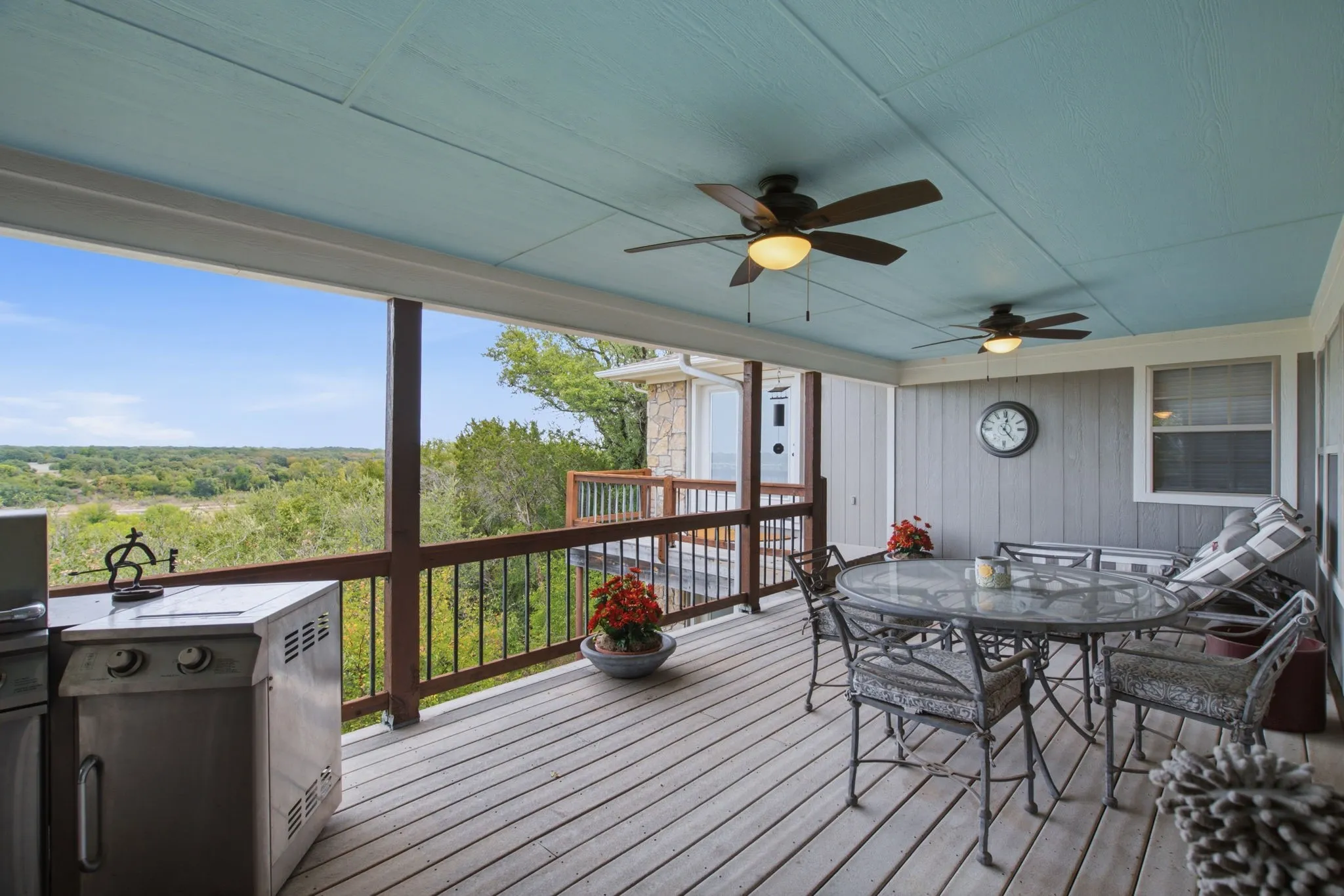 Spacious covered deck featuring wood-finish flooring, dual ceiling fans with lighting, and a built-in outdoor grill​​‌​​​​‌​​‌‌​‌‌​​​‌‌​‌​‌​‌​​​‌​​ station