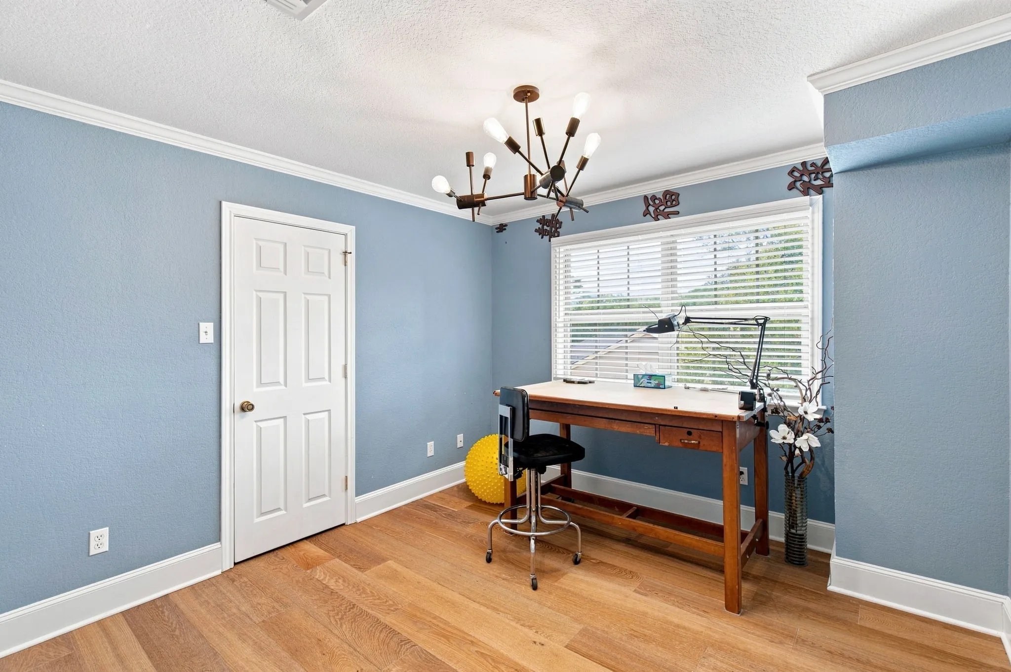 Wood-finish flooring, crown molding, and a modern chandelier fixture