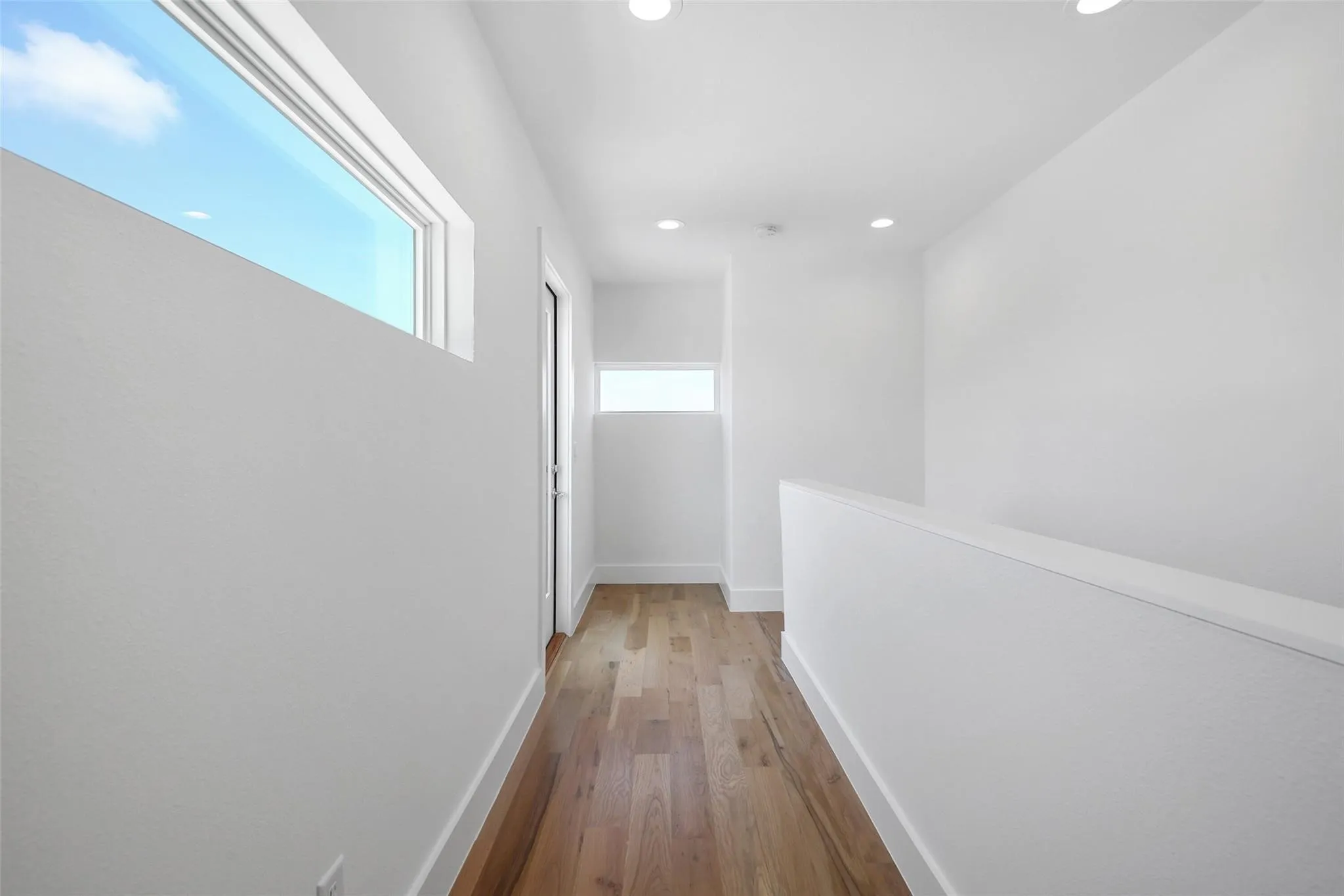 Hardwood flooring, recessed lighting, white painted walls, and high-set windows