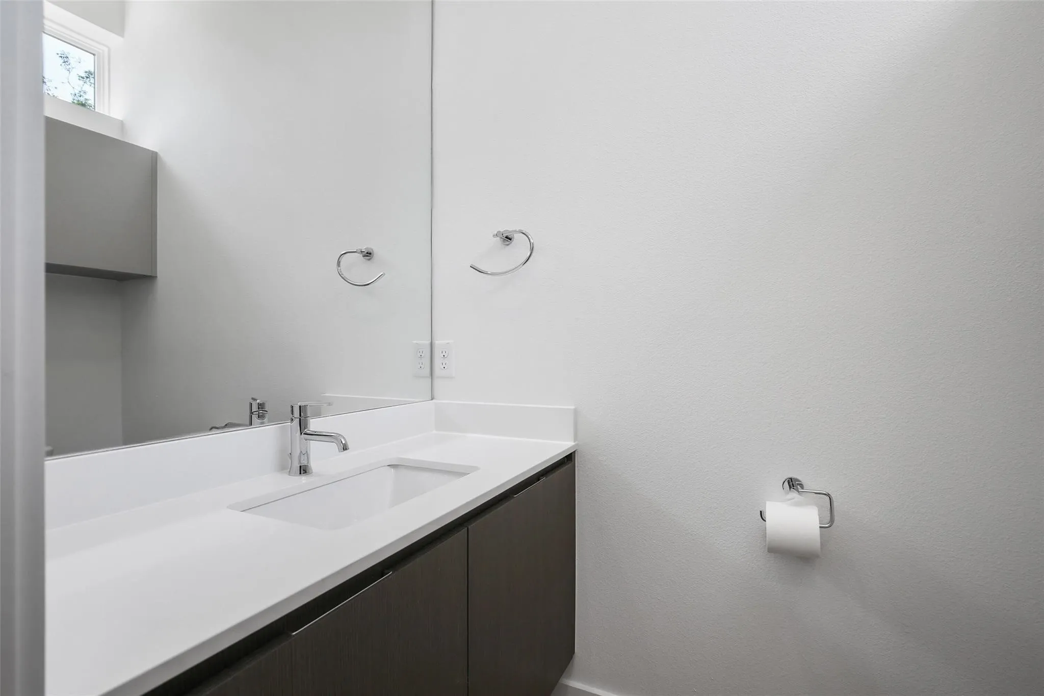 Integrated sink with chrome faucet, full-width vanity mirror, and built-in vanity cabinetry