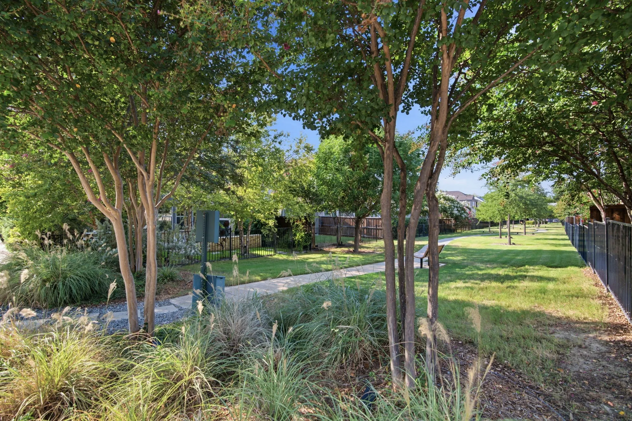 Landscaped grounds featuring mature trees, a paved pathway, and a grassy area
