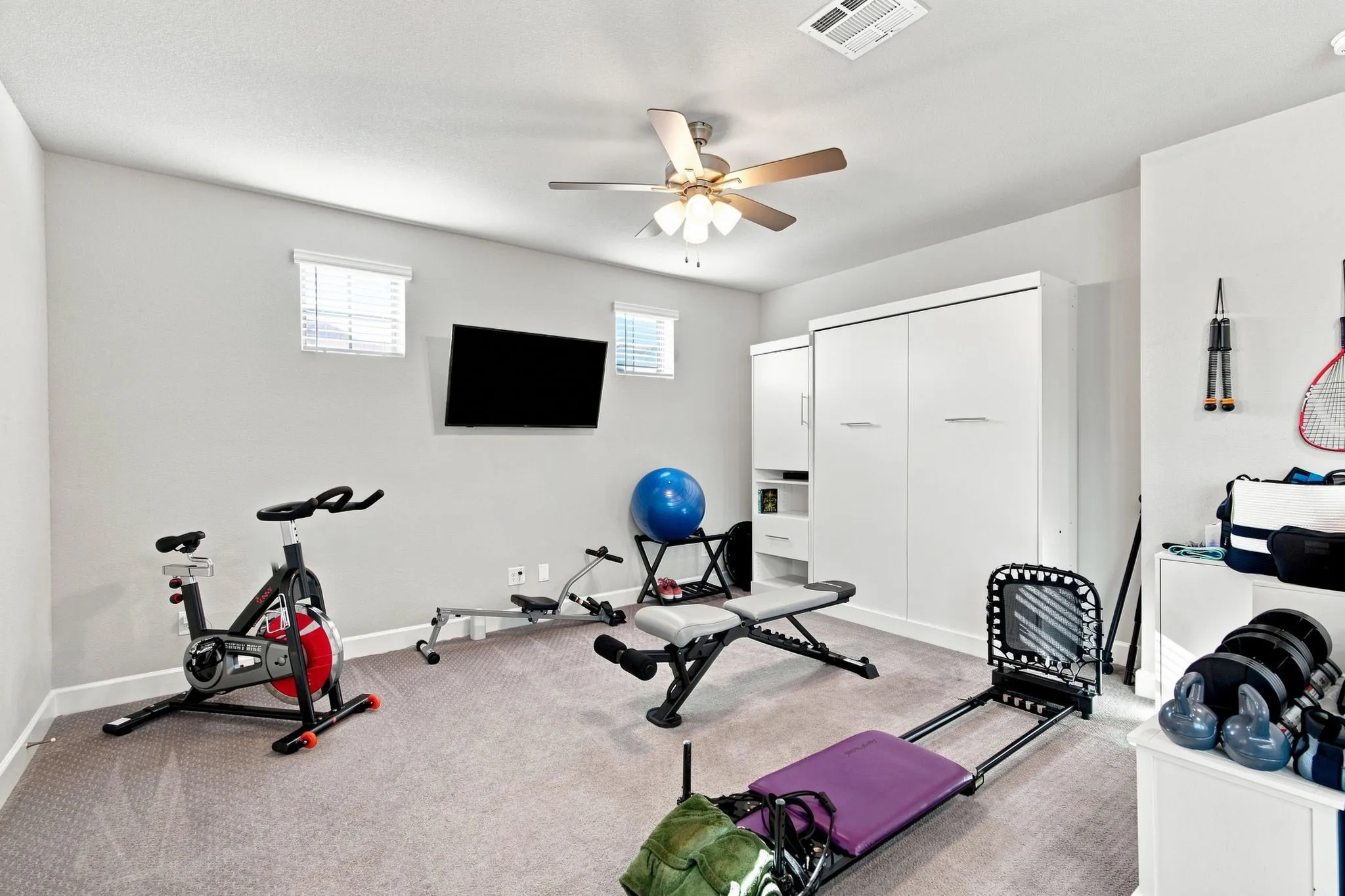 Recessed lighting, ceiling fan, two windows with blinds, and built-in white cabinetry