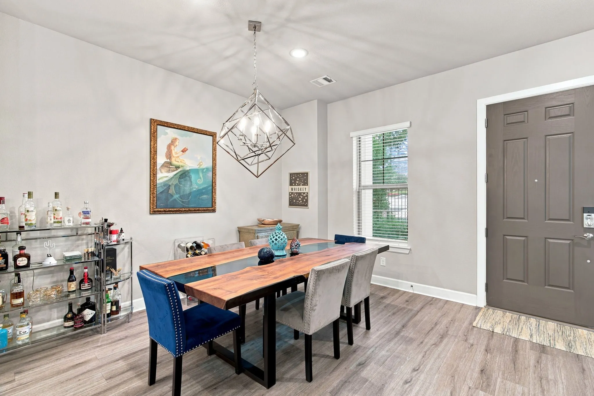 Wood-finish flooring throughout, featuring a geometric chandelier and a window with blinds