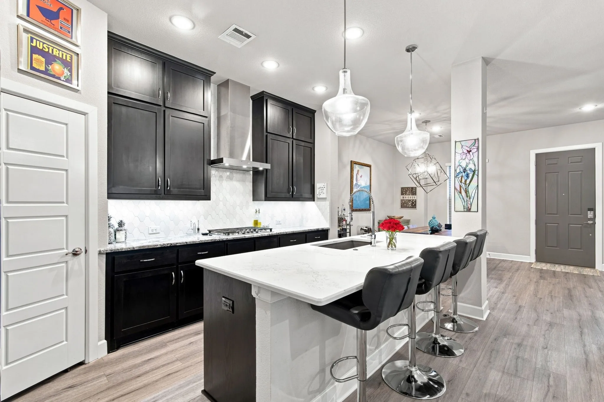 Kitchen featuring dark wood cabinetry, white countertops, stainless steel range hood, recessed lighting, and pendant lighting fixtures