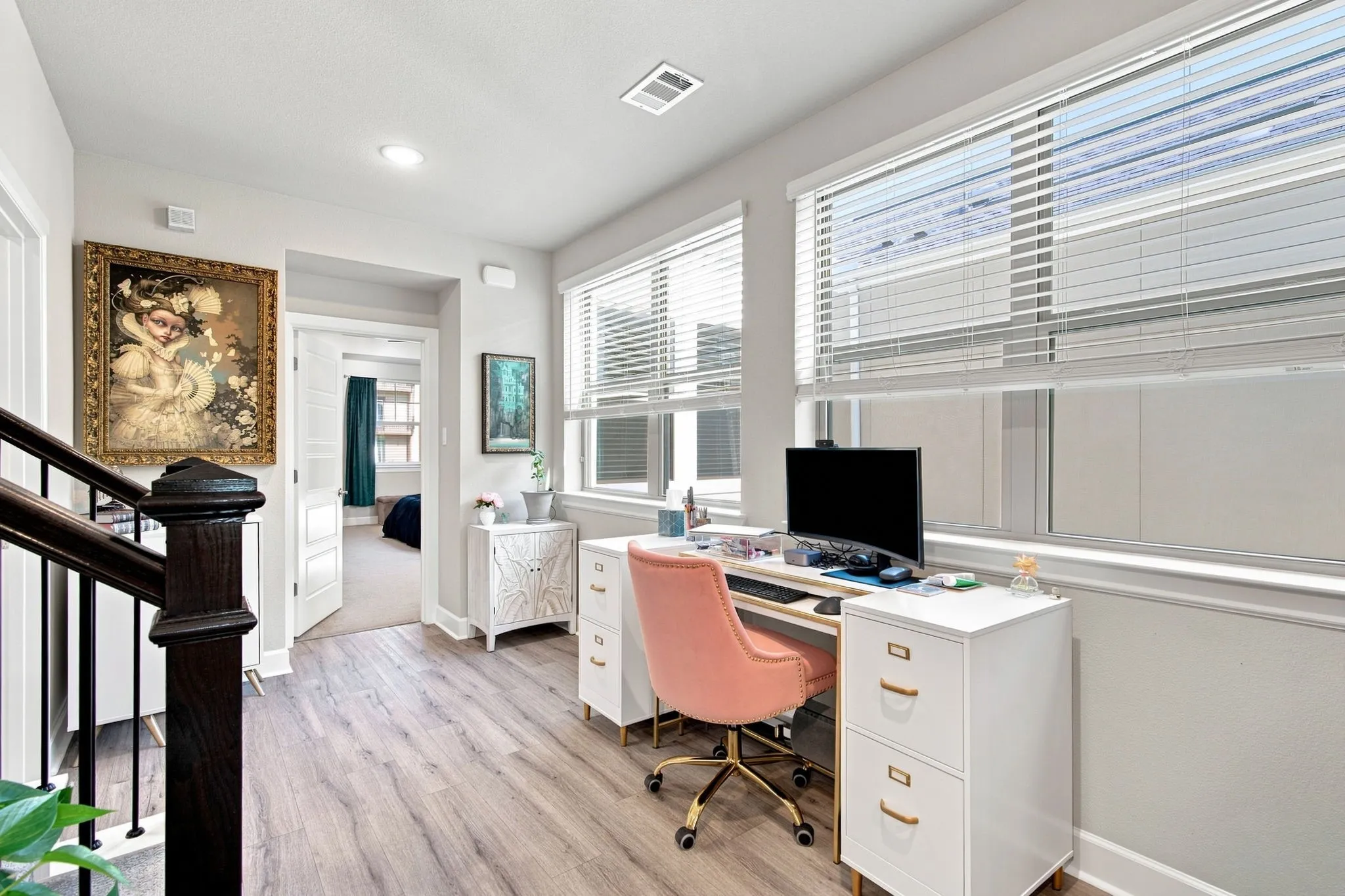 Wood-finish flooring, multiple windows with blinds, recessed lighting, and a dark wood newel post