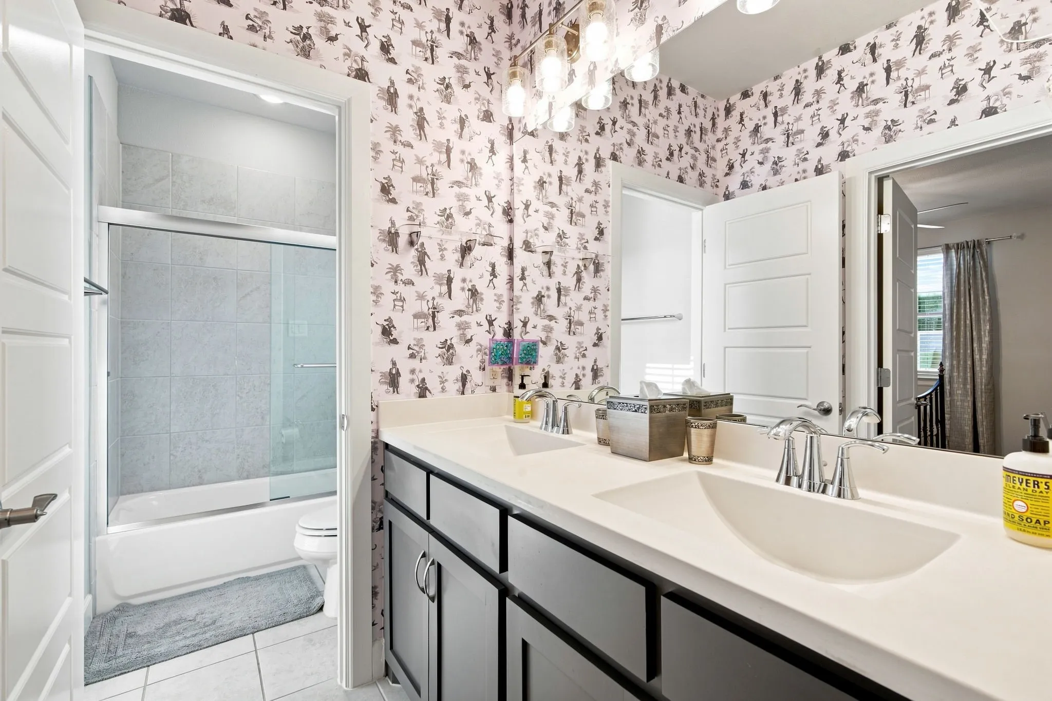 Dual vanity with integrated sinks, modern light fixture, and patterned wall covering