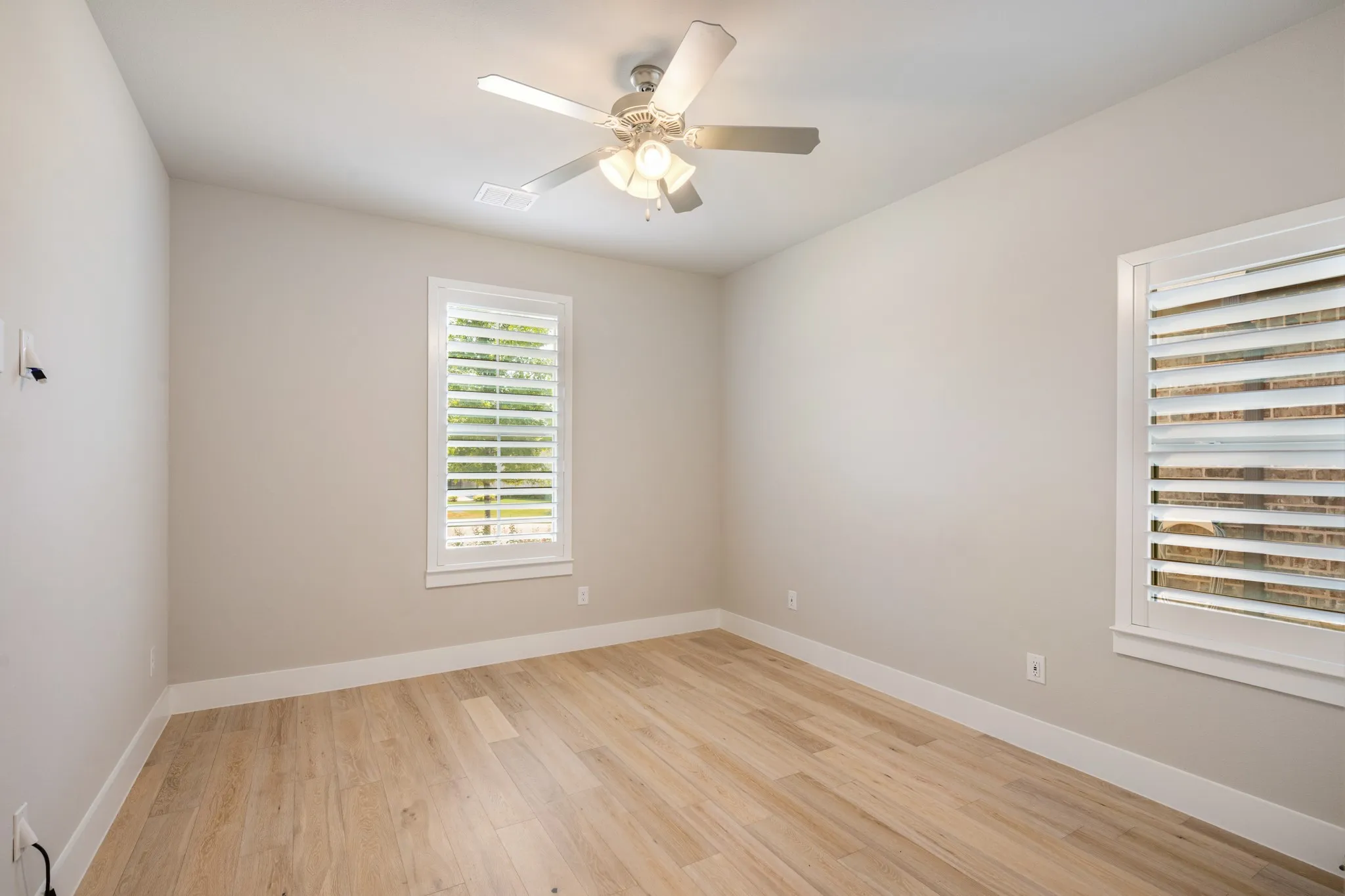 Secondary bedroom features hard surface flooring, a fan and multiple windows for natural light. Custom plantation shutters thru-out.