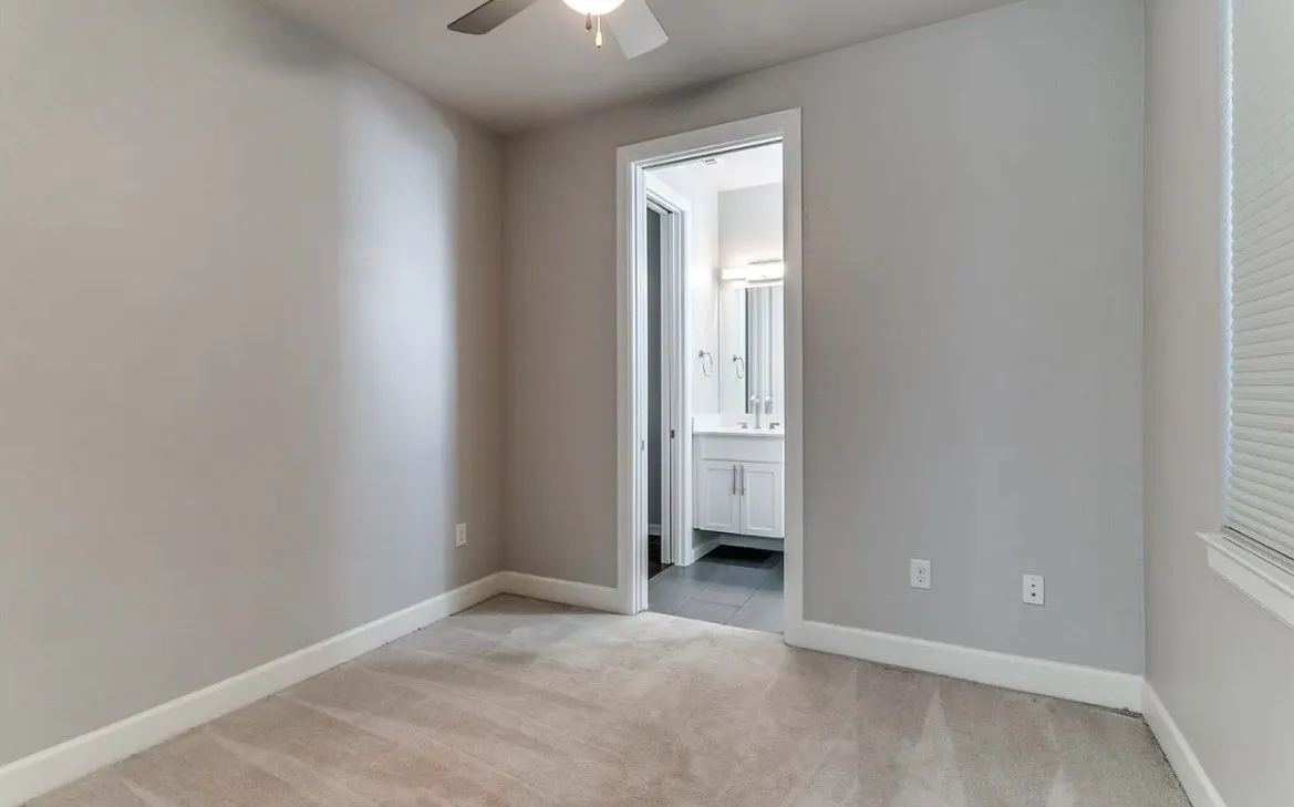 Plush carpet flooring, neutral painted walls, ceiling fan, and window with blinds