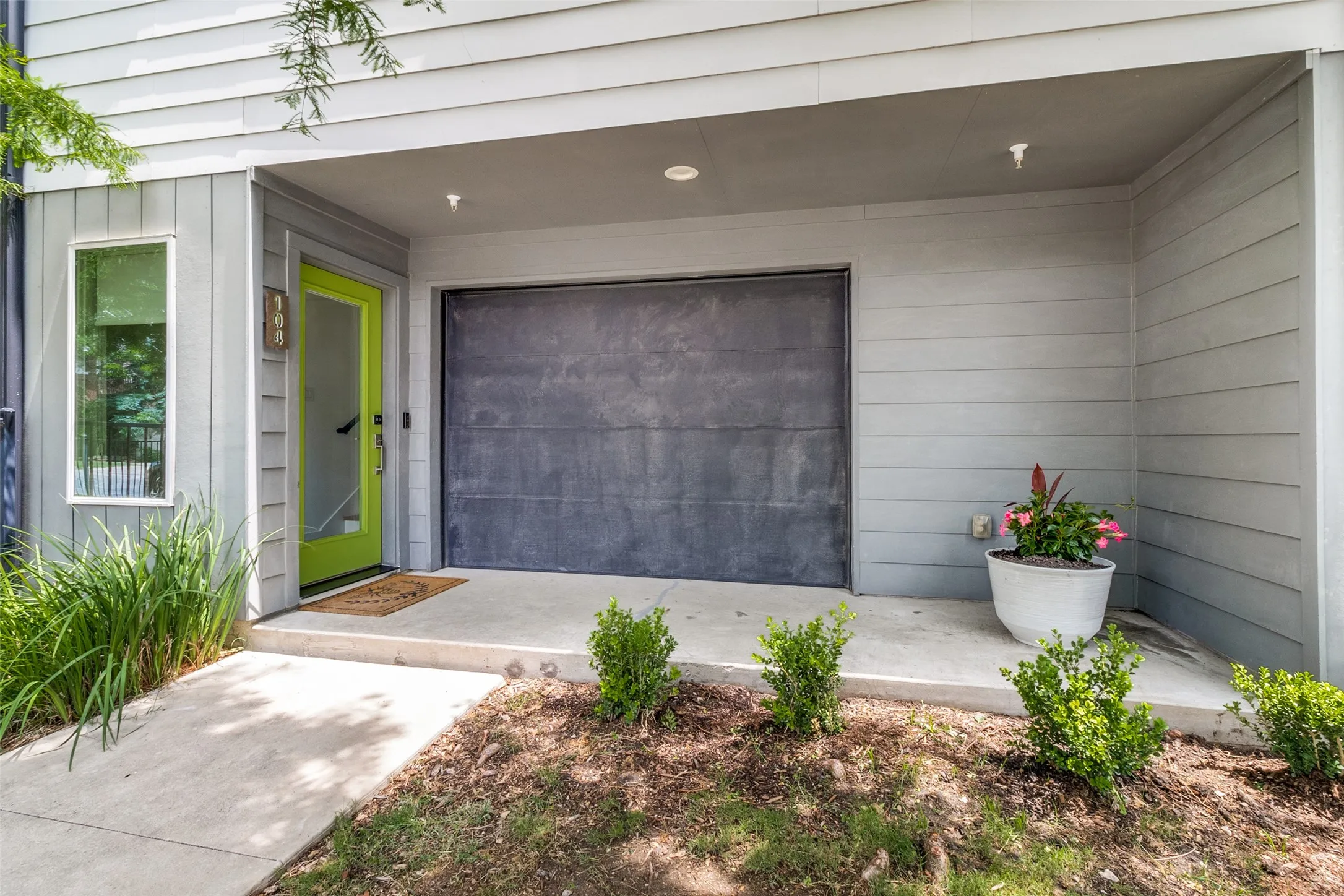 Front patio with unique garage door that opens to the private front yard for added space.