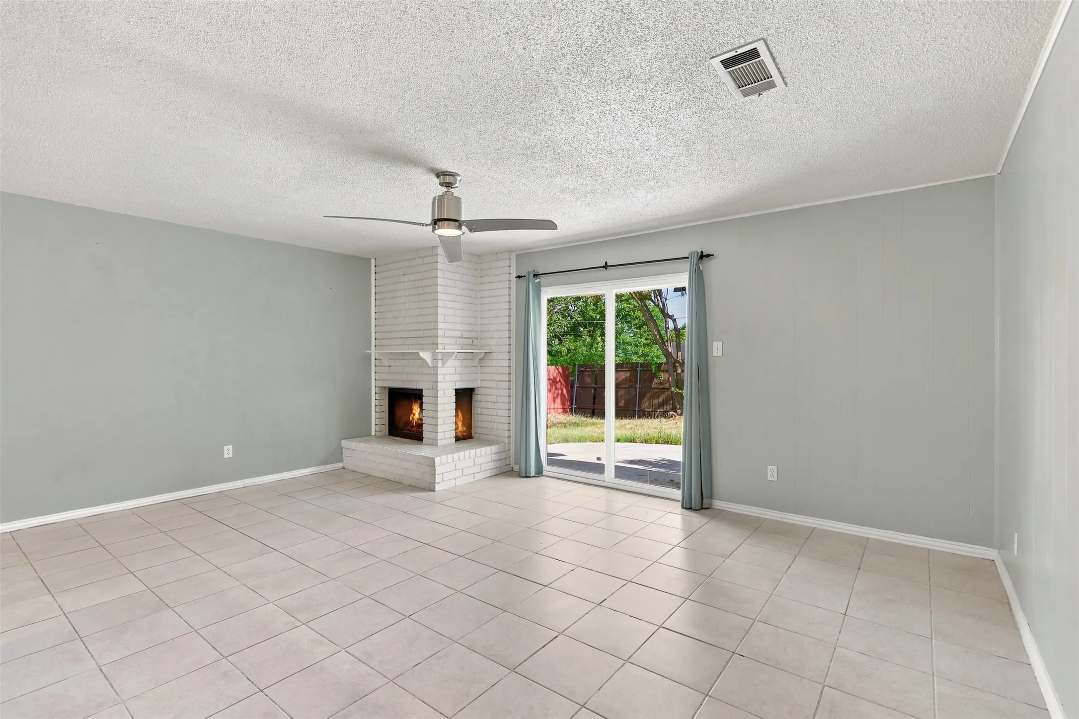 White brick fireplace with hearth, tile flooring, and sliding glass doors to the exterior