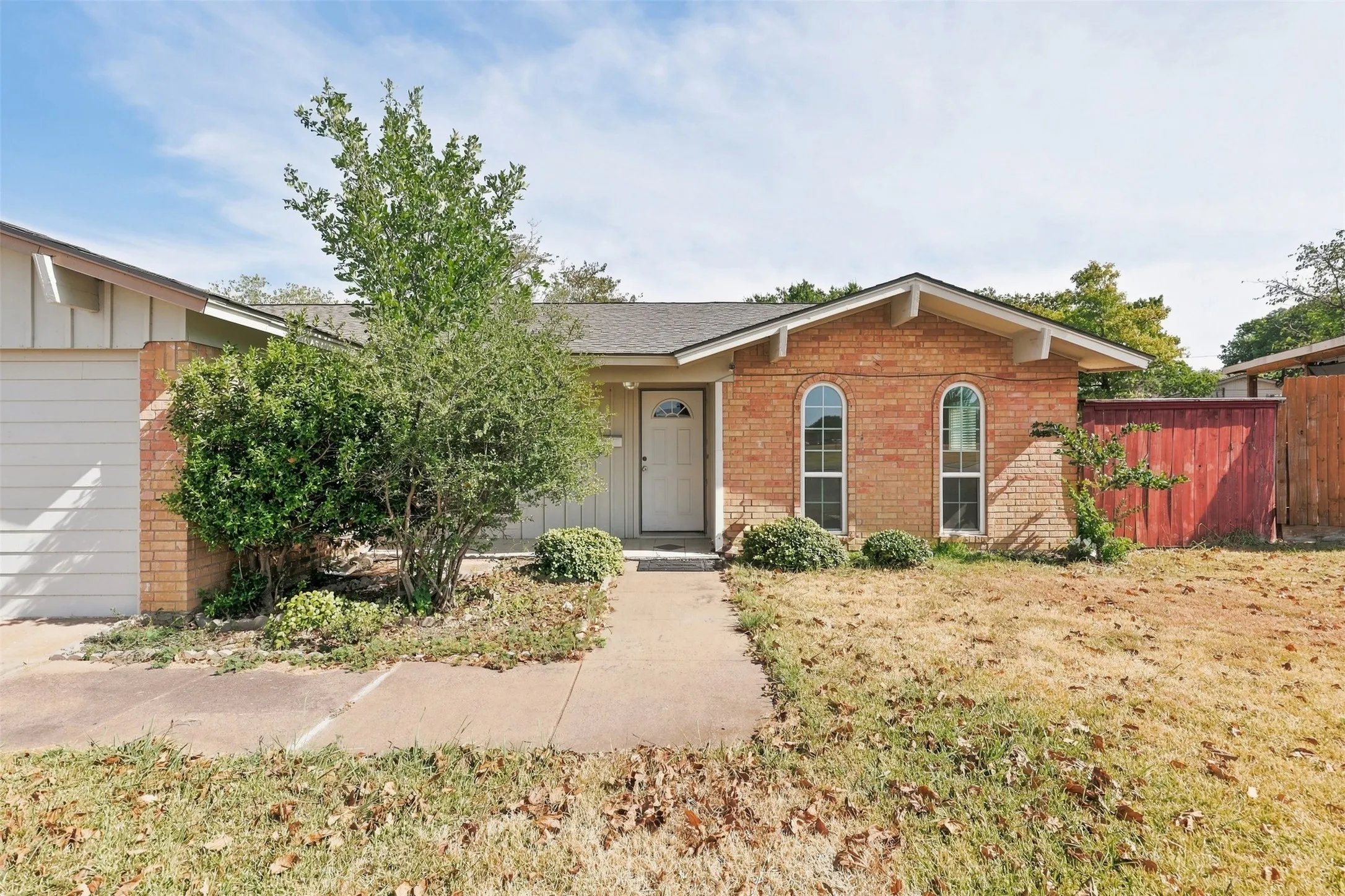 Brick exterior with white trim, arched windows, and a paved walkway
