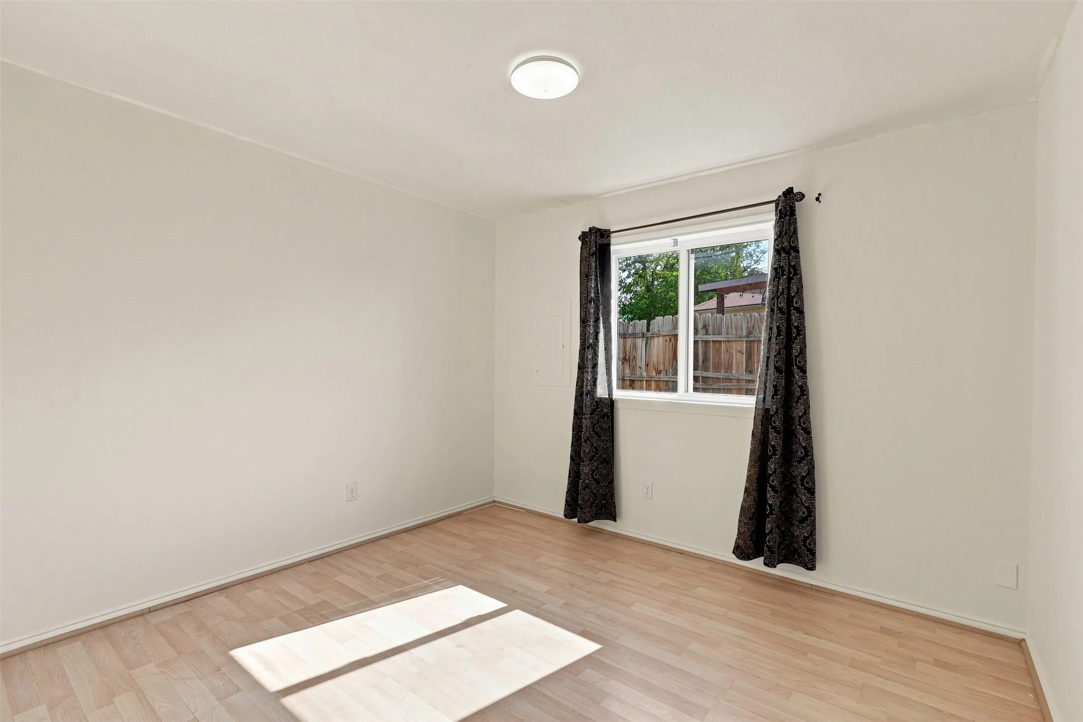 Wood-finish flooring, white walls, and a modern ceiling light fixture