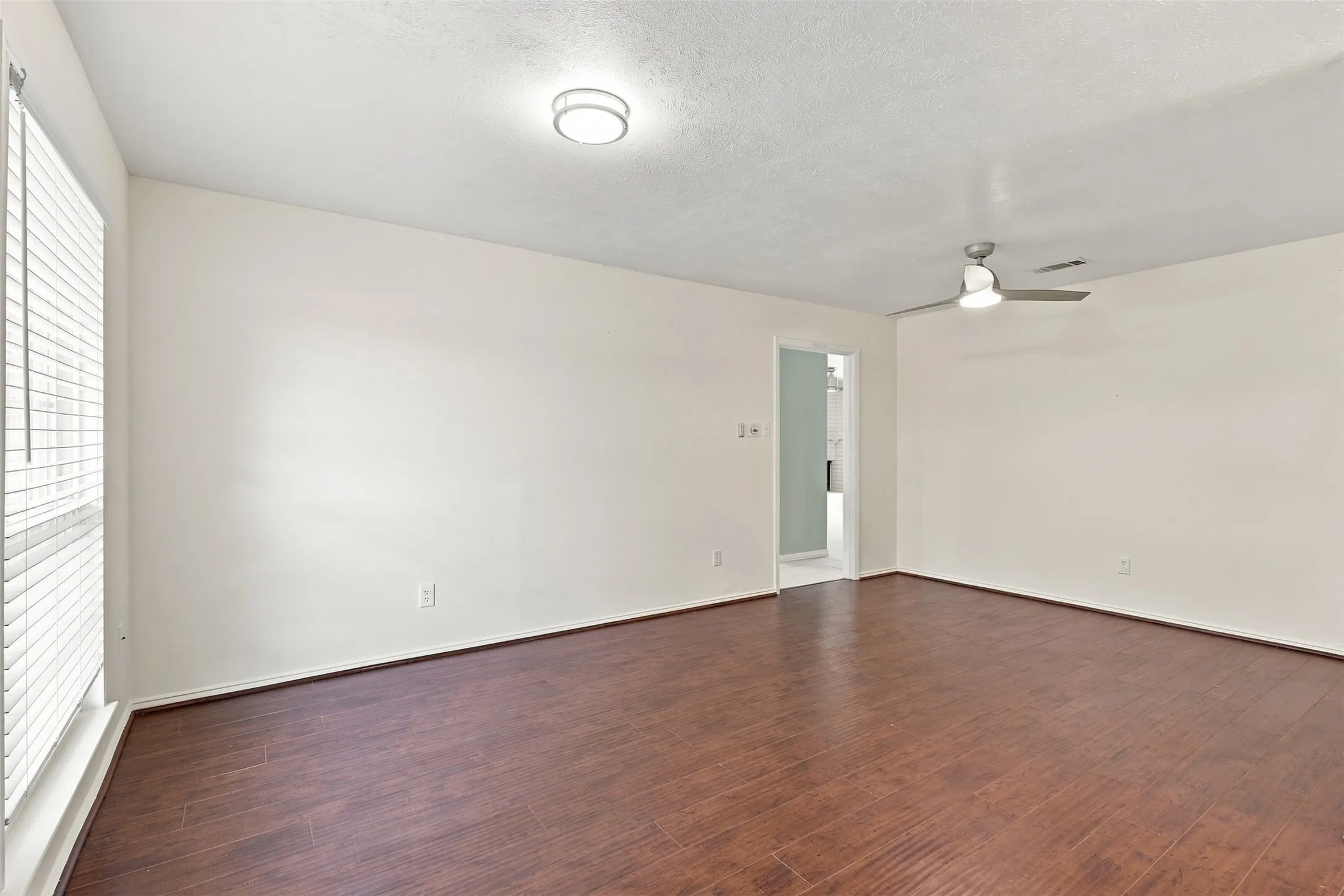 Spacious room featuring wood-finish flooring, a contemporary ceiling fan, and a flush-mount ceiling light